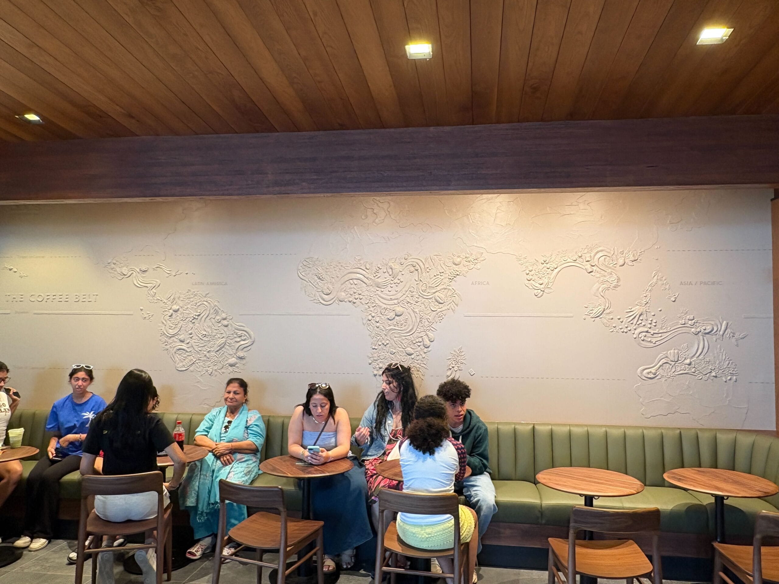 People relaxing at a Starbucks cafe in Disney Springs, with a world map embossed on the newly refurbished wall.