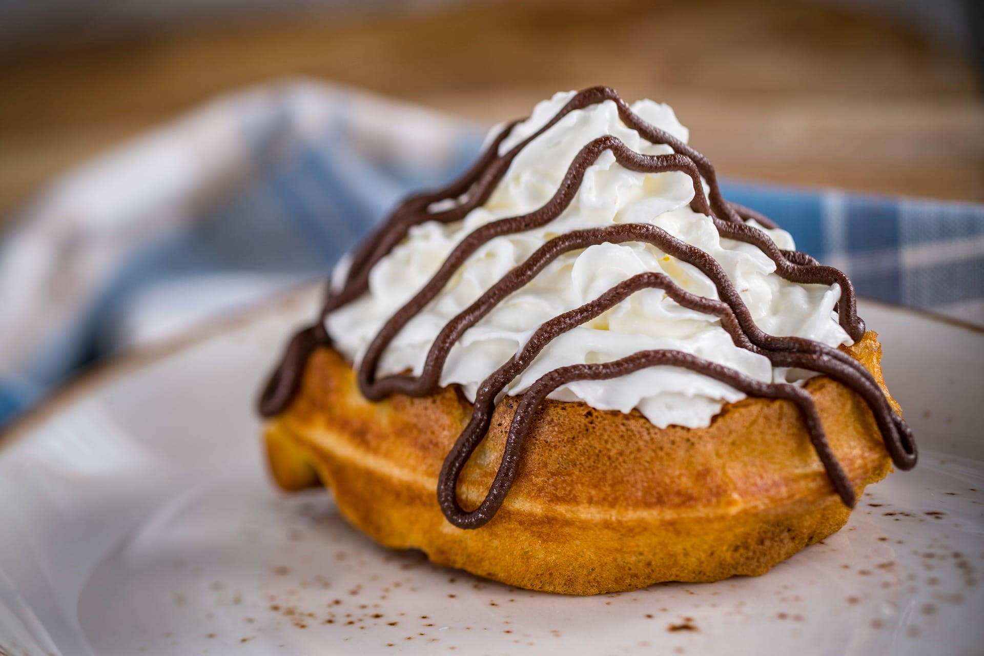 A waffle topped with whipped cream and chocolate sauce, inspired by EPCOT Food & Wine Festival full menus.