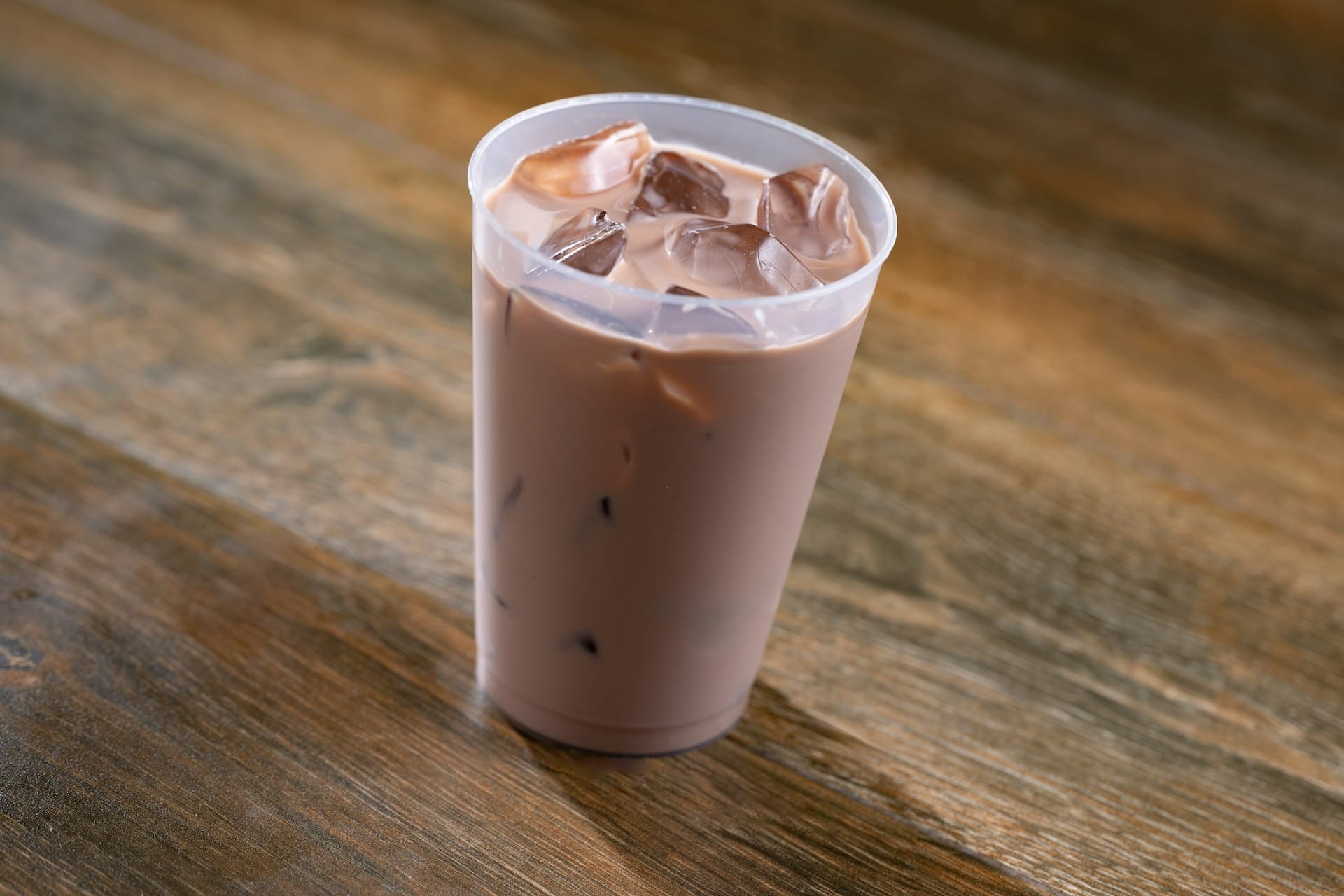 A plastic cup of iced chocolate milk sits on a wooden surface at the EPCOT Food & Wine Festival.