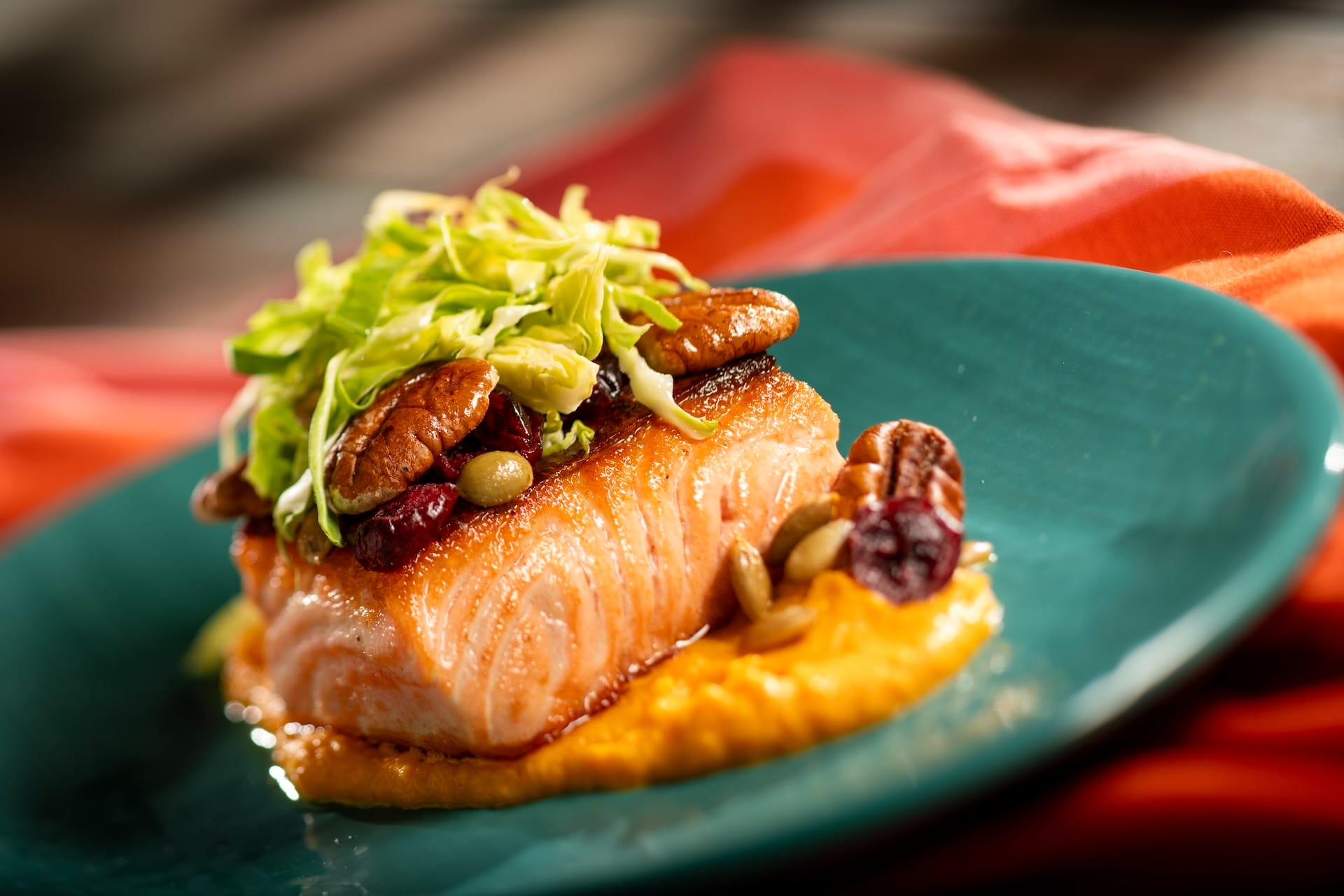 A cooked salmon fillet on orange puree, part of the 2025 full menus at EPCOT Food & Wine Festival.