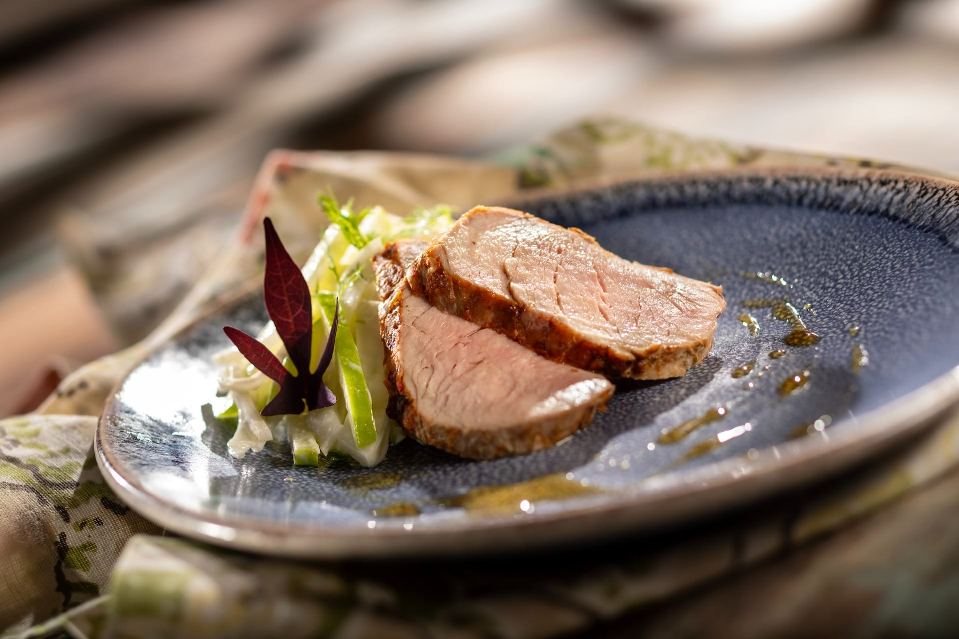 Two slices of cooked pork tenderloin with salad, as featured on the 2025 menus at the EPCOT Food & Wine Festival.