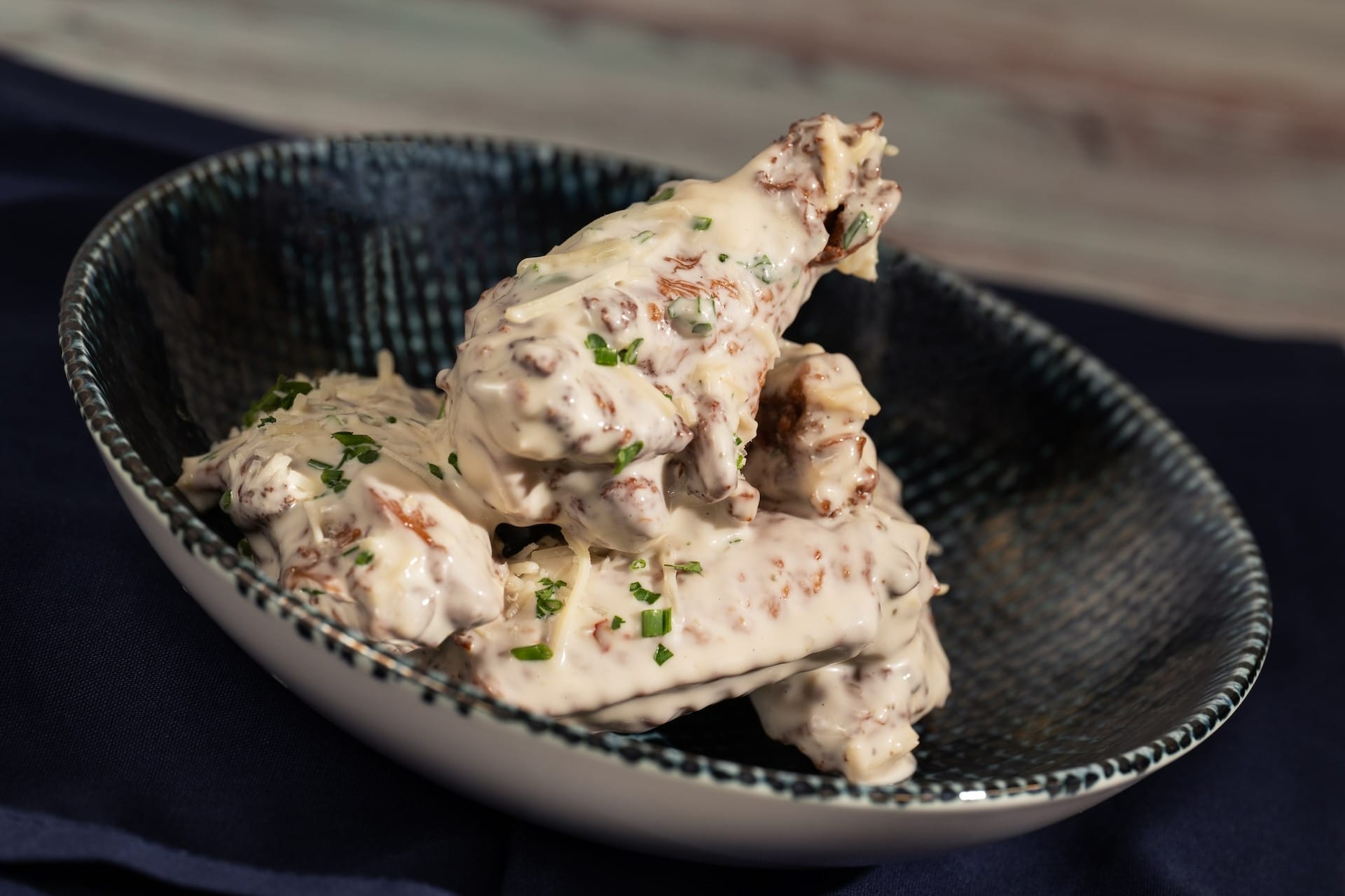 Chicken wings in creamy white sauce, garnished with herbs—an EPCOT Food & Wine Festival 2025 menus highlight.