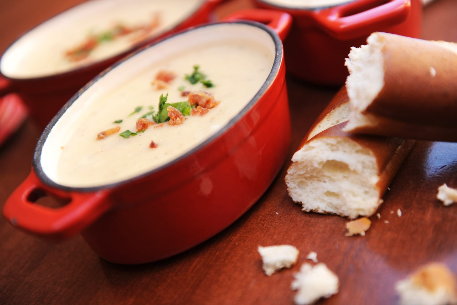 Creamy soup garnished with herbs in a red bowl, featured on 2025 menus at the EPCOT Food & Wine Festival.