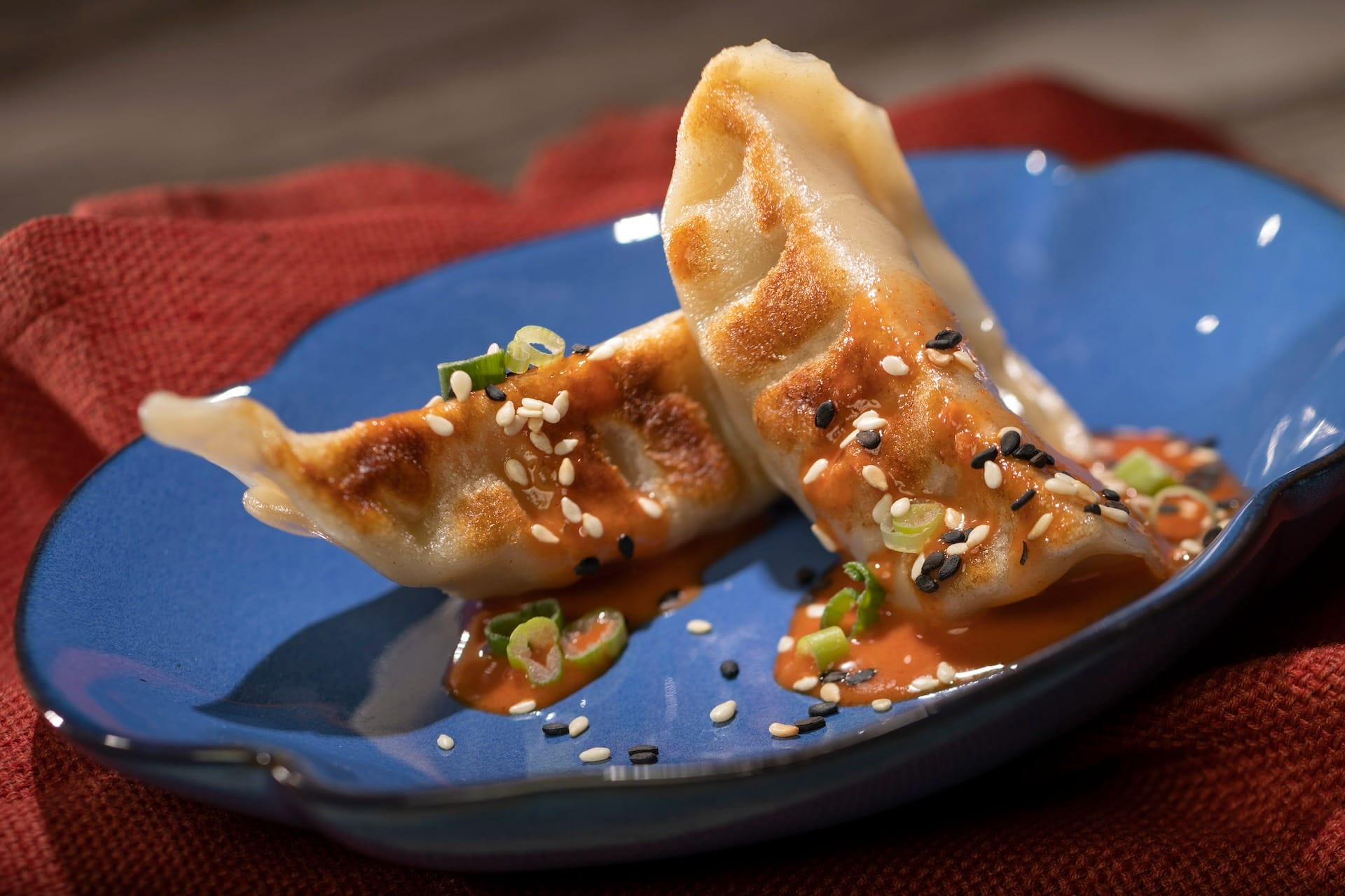 Two pan-fried dumplings with sauce, sesame seeds, and green onions from the 2025 EPCOT Food & Wine Festival menus.
