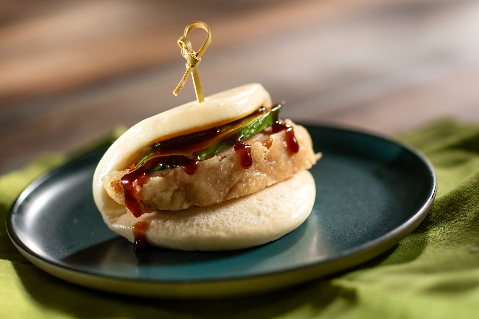 A steamed bao bun with fried chicken, cucumber, and sauce—just like those at the EPCOT Food & Wine Festival 2025.