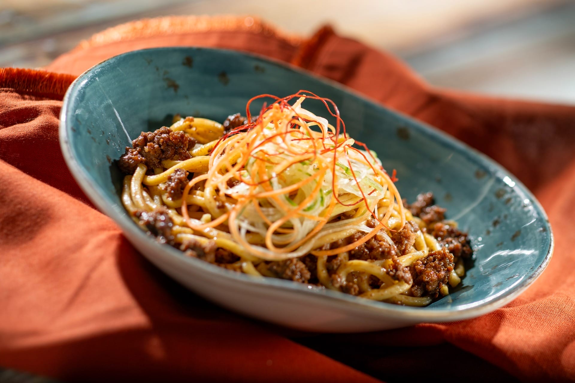 A bowl of noodles with ground meat and veggies, inspired by the 2025 EPCOT Food & Wine Festival full menus.