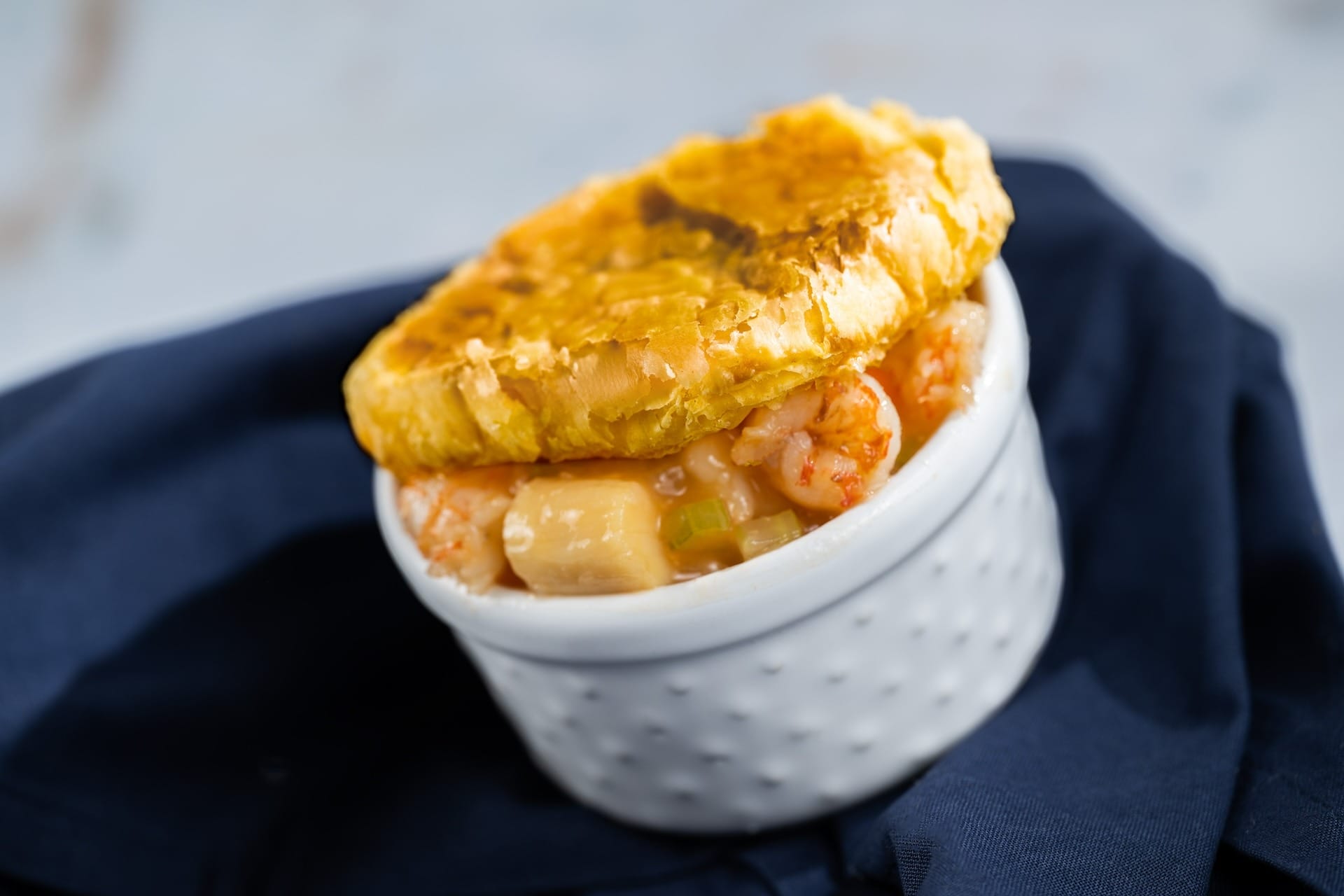 A seafood pot pie with a golden crust in a white ramekin, inspired by EPCOT Food & Wine Festival 2025 menus.