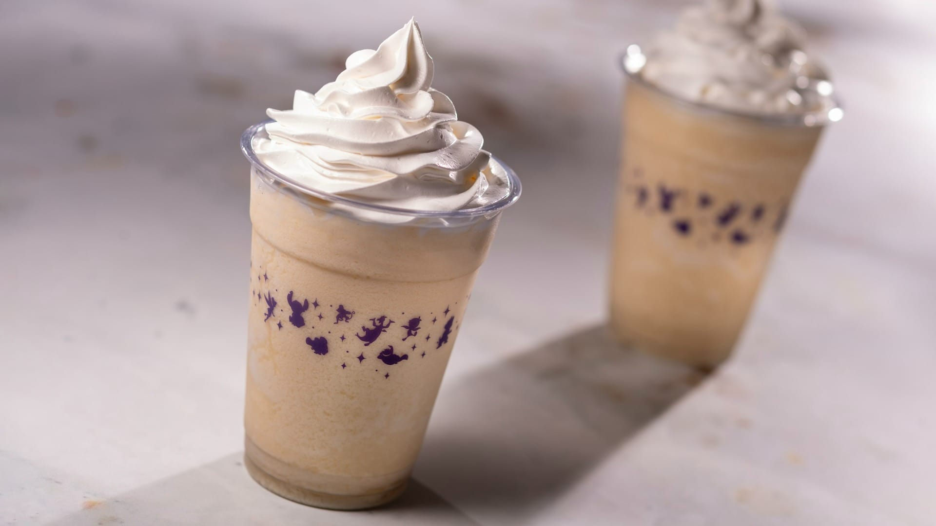 Two creamy, light brown milkshakes sit topped with whipped cream—perfect for the 2025 EPCOT Food & Wine Festival.