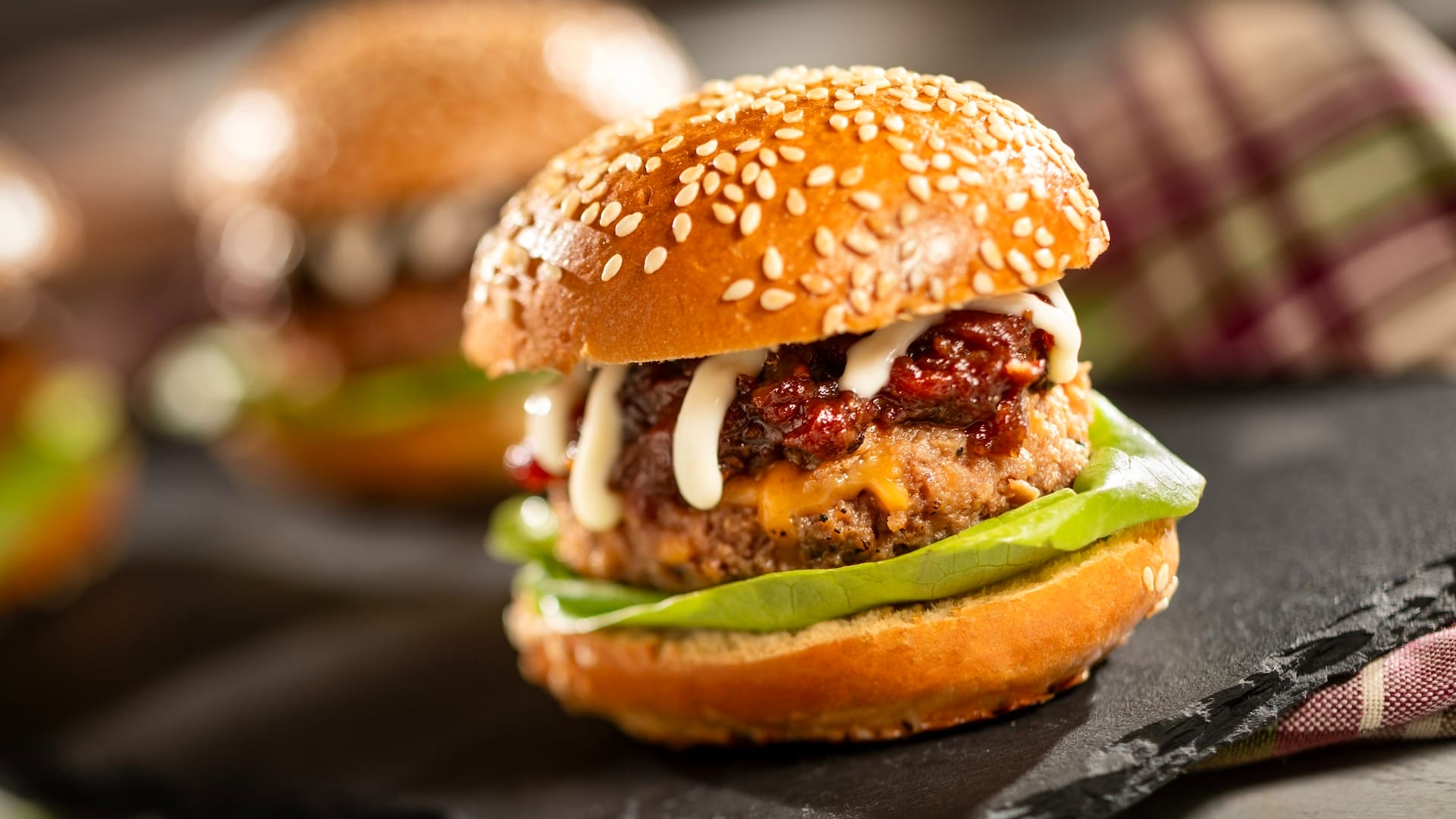 A cheeseburger with lettuce, tomato, sauce, and a sesame seed bun—perfect for the EPCOT Food & Wine Festival.