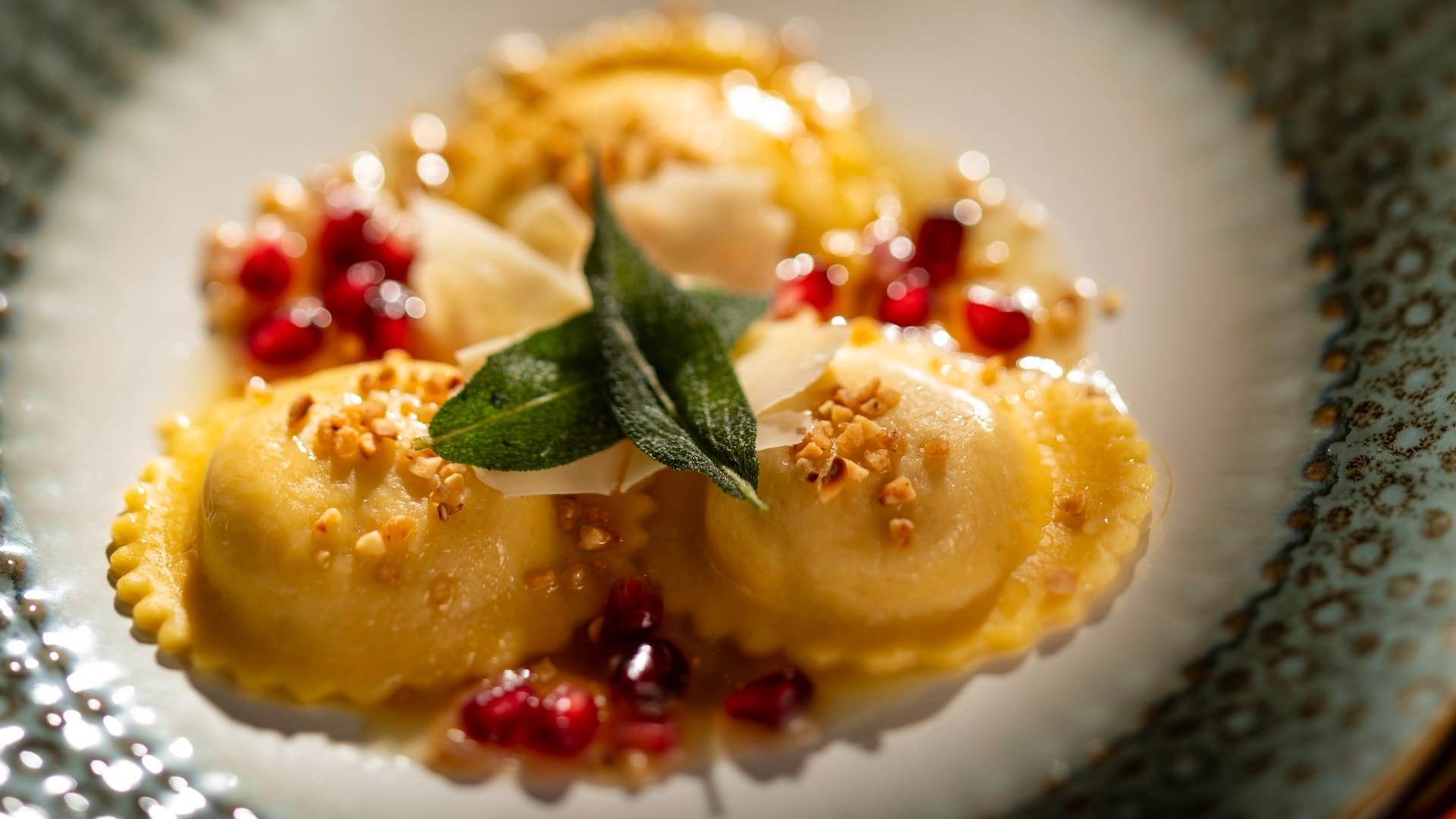 Three ravioli topped with sage, cheese, pomegranate seeds, and nuts from the EPCOT Food & Wine Festival 2025 menus.