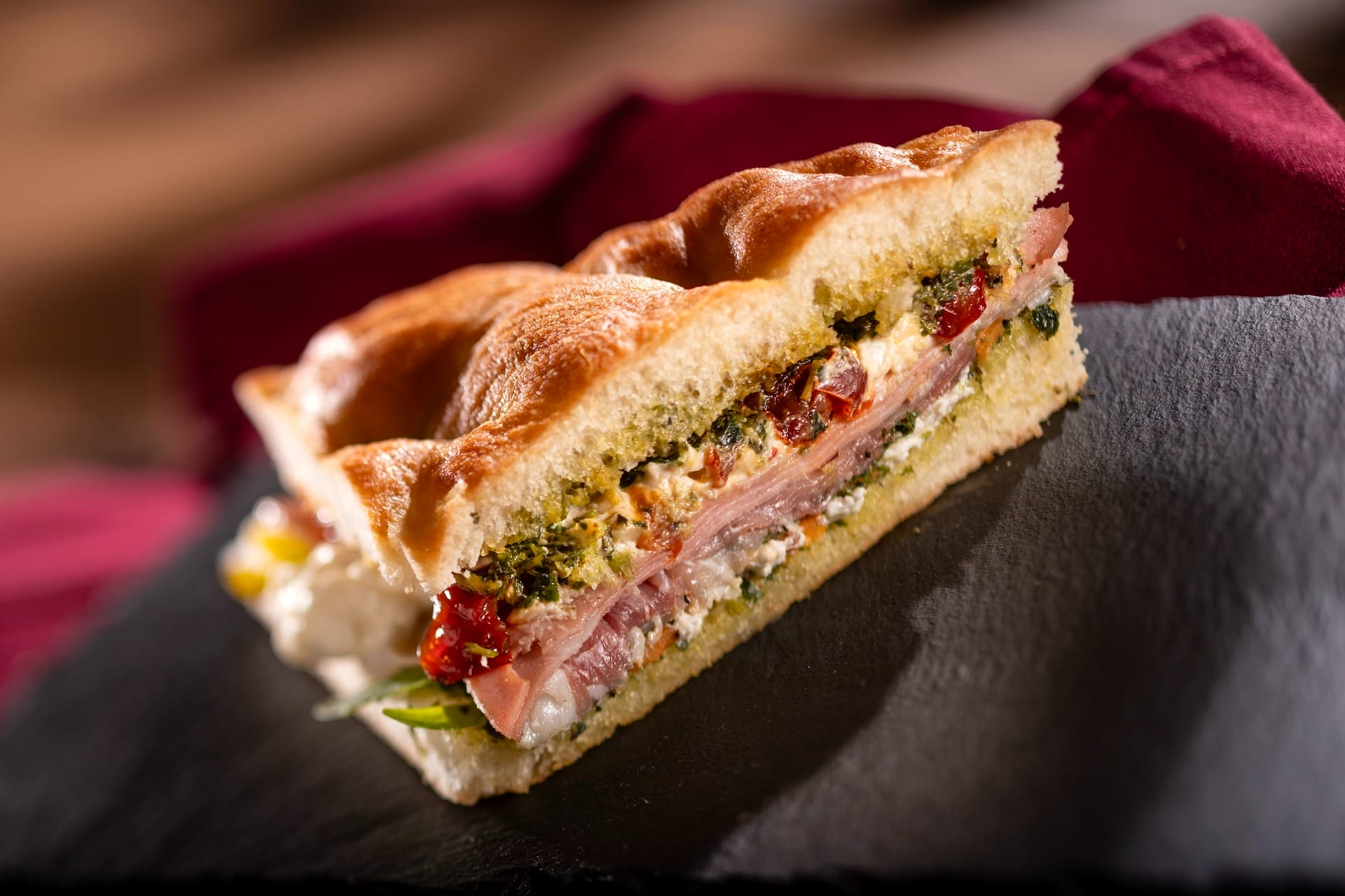 Close-up of a gourmet sandwich featured on the 2025 menus at the EPCOT Food & Wine Festival, served on a slate plate.
