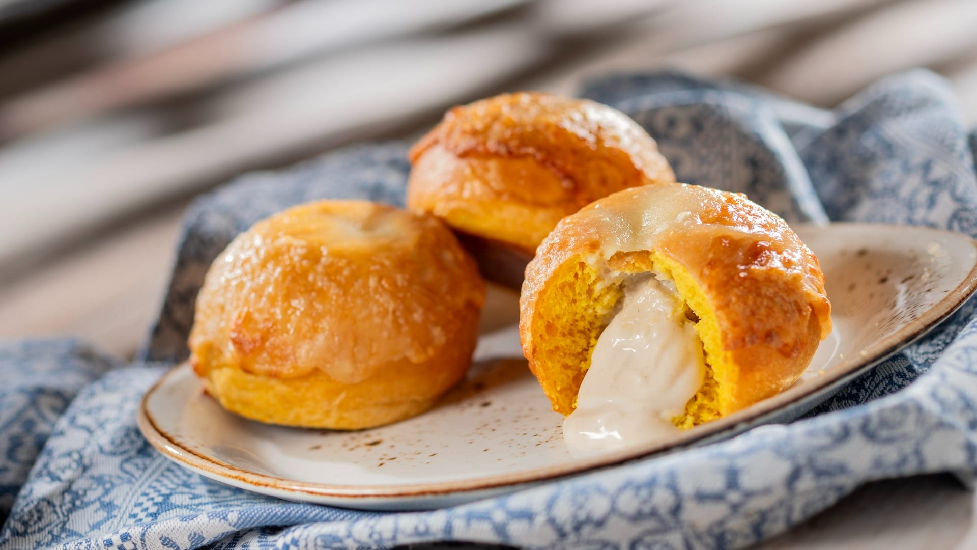 Three cream-filled pastries on a plate, one cut open to reveal the filling—perfect for the EPCOT Food & Wine Festival.