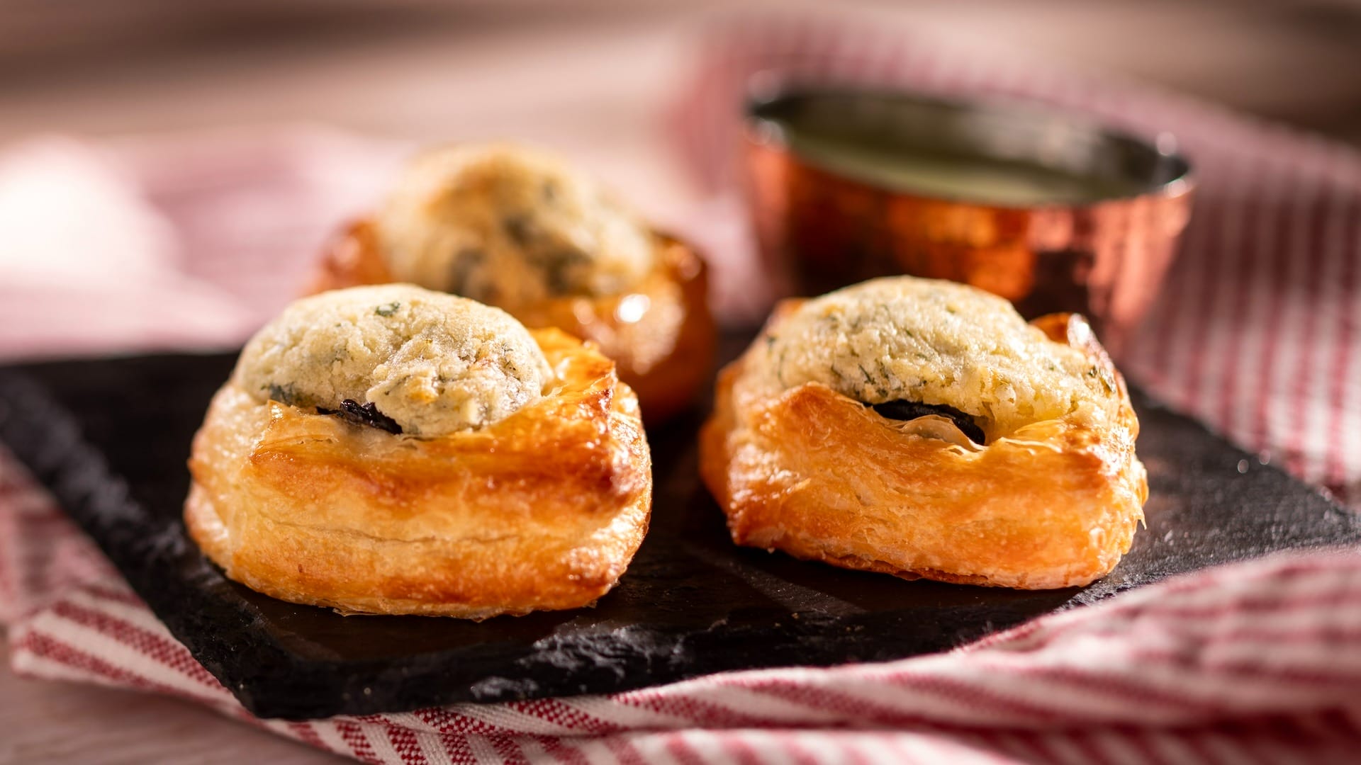 Three golden puff pastry appetizers from the EPCOT Food & Wine Festival, served with creamy filling and dipping sauce.