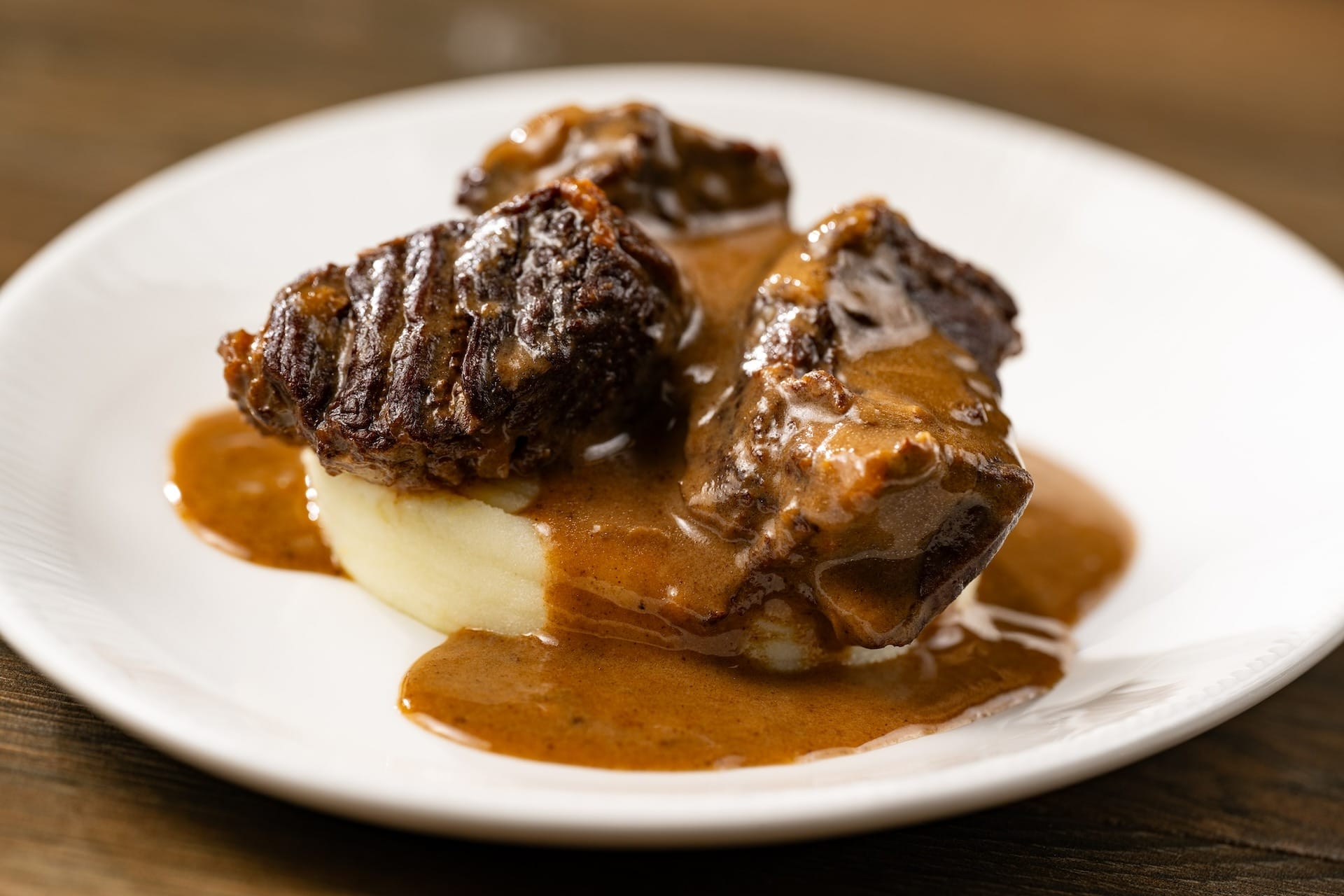 Braised beef short ribs with brown gravy over mashed potatoes, featured on 2025 EPCOT Food & Wine Festival menus.