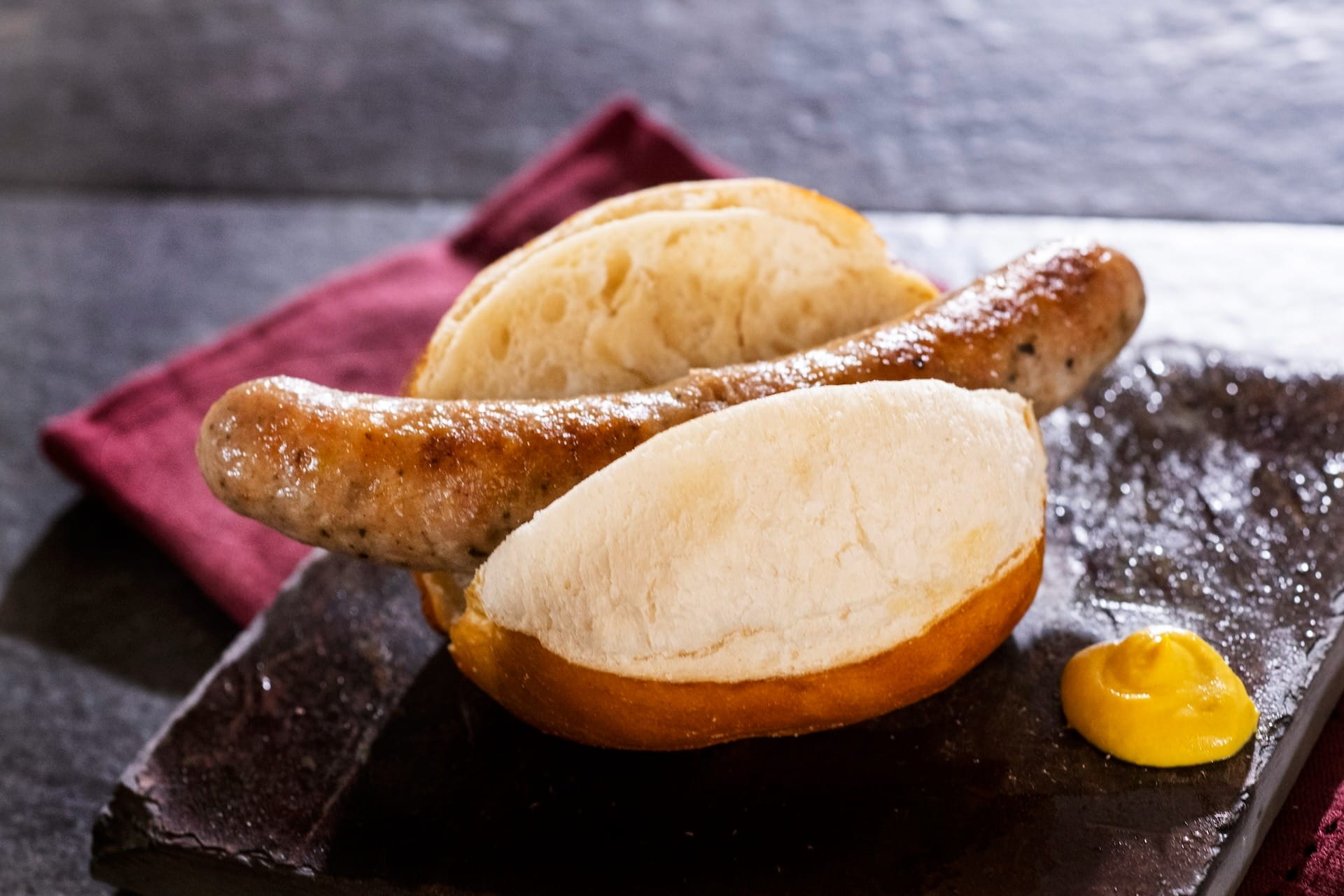 A grilled sausage in a crusty bun, ready for the 2025 menus at the EPCOT Food & Wine Festival.