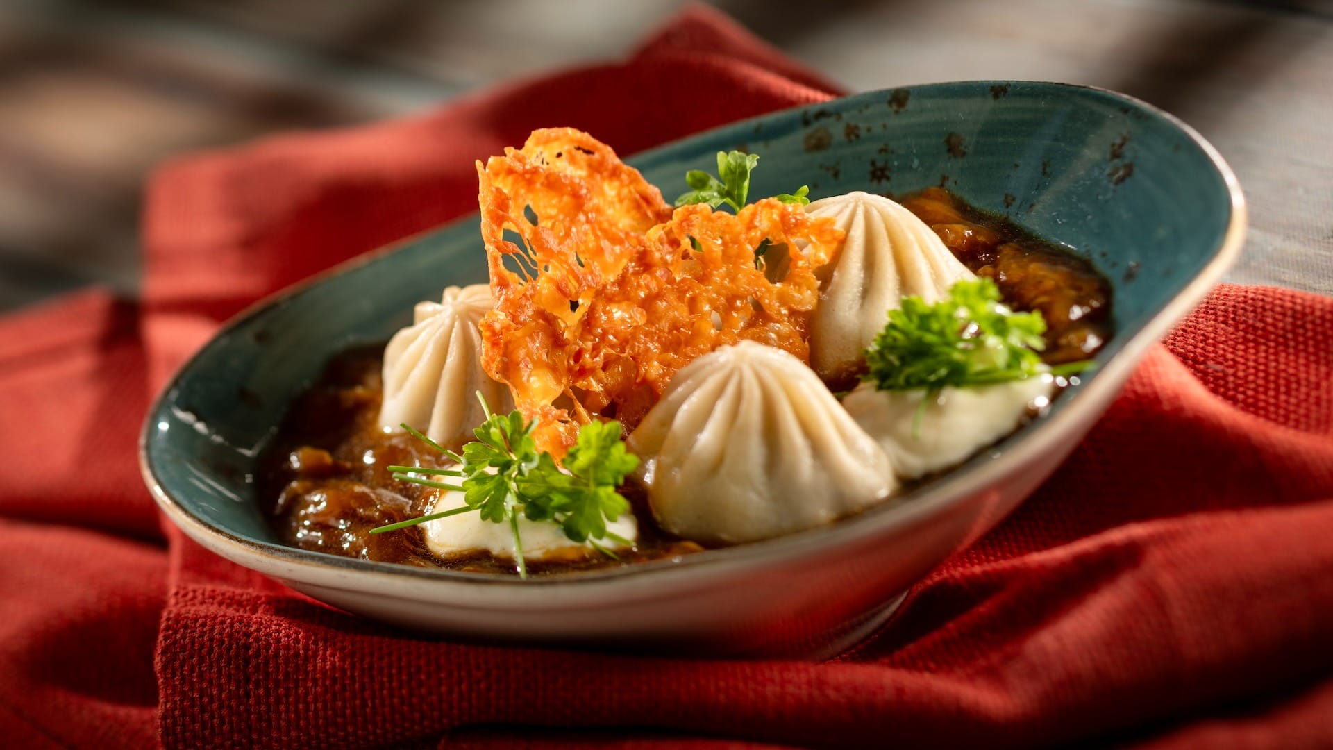 Three steamed dumplings with garnish and crispy topping, served EPCOT Festival style at a themed food booth.