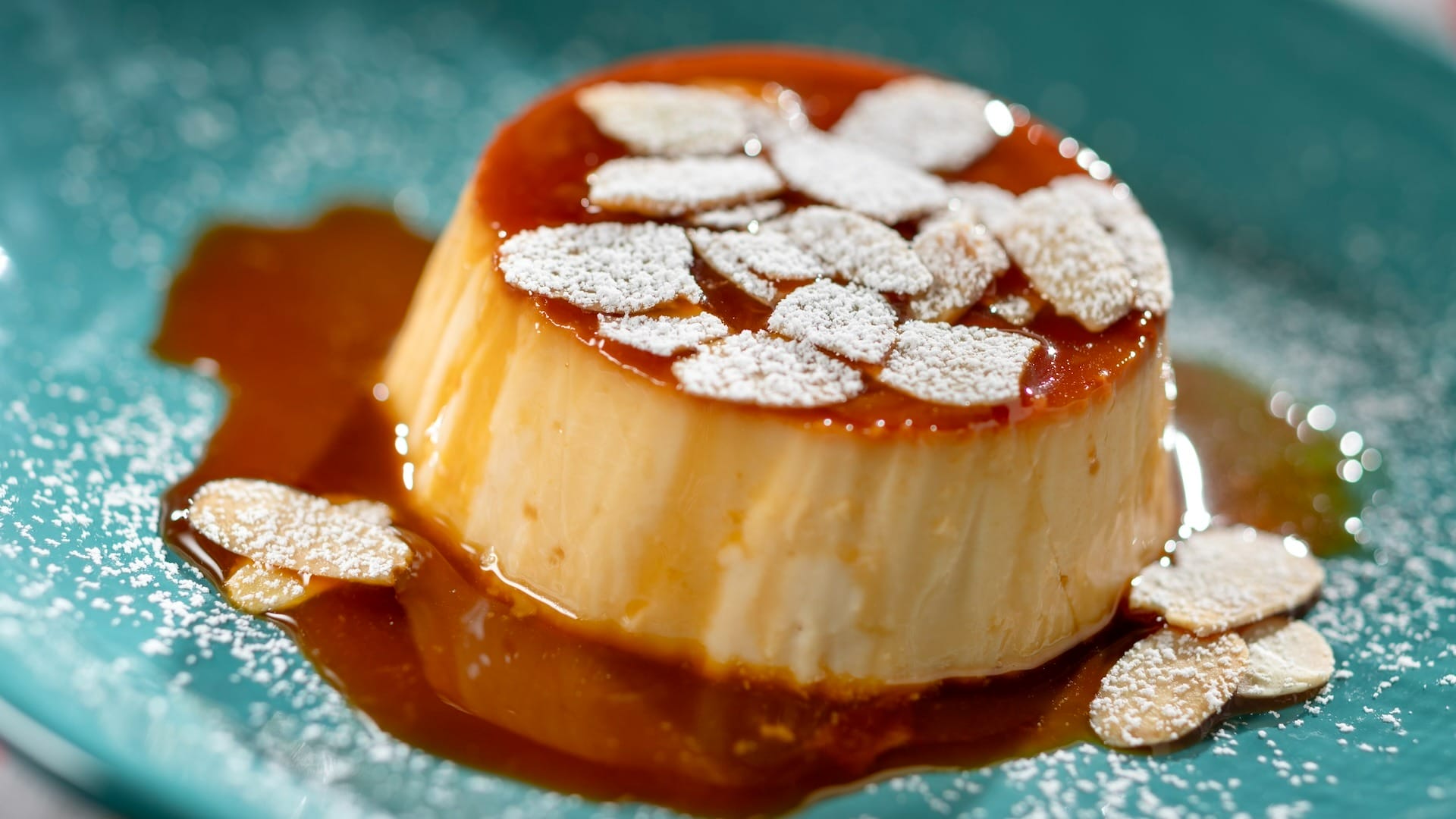 A creamy flan dessert topped with sliced almonds, featured on the 2025 menus at the EPCOT Food & Wine Festival.