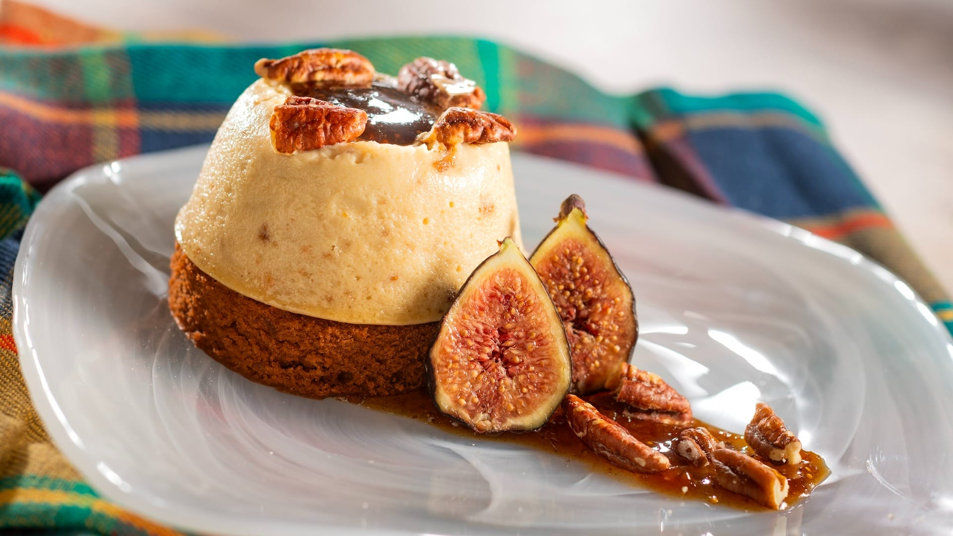 A dessert from the EPCOT Food & Wine Festival menus—cake, creamy layers, pecans, figs, and sauce on a white plate.