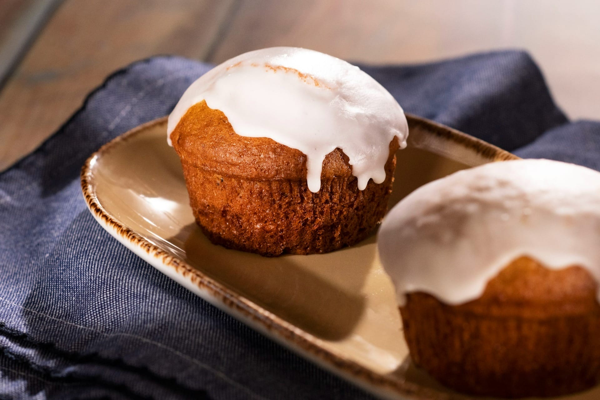 Two cupcakes with white icing on a tan plate, styled for the 2025 menus at the Food & Wine Festival.