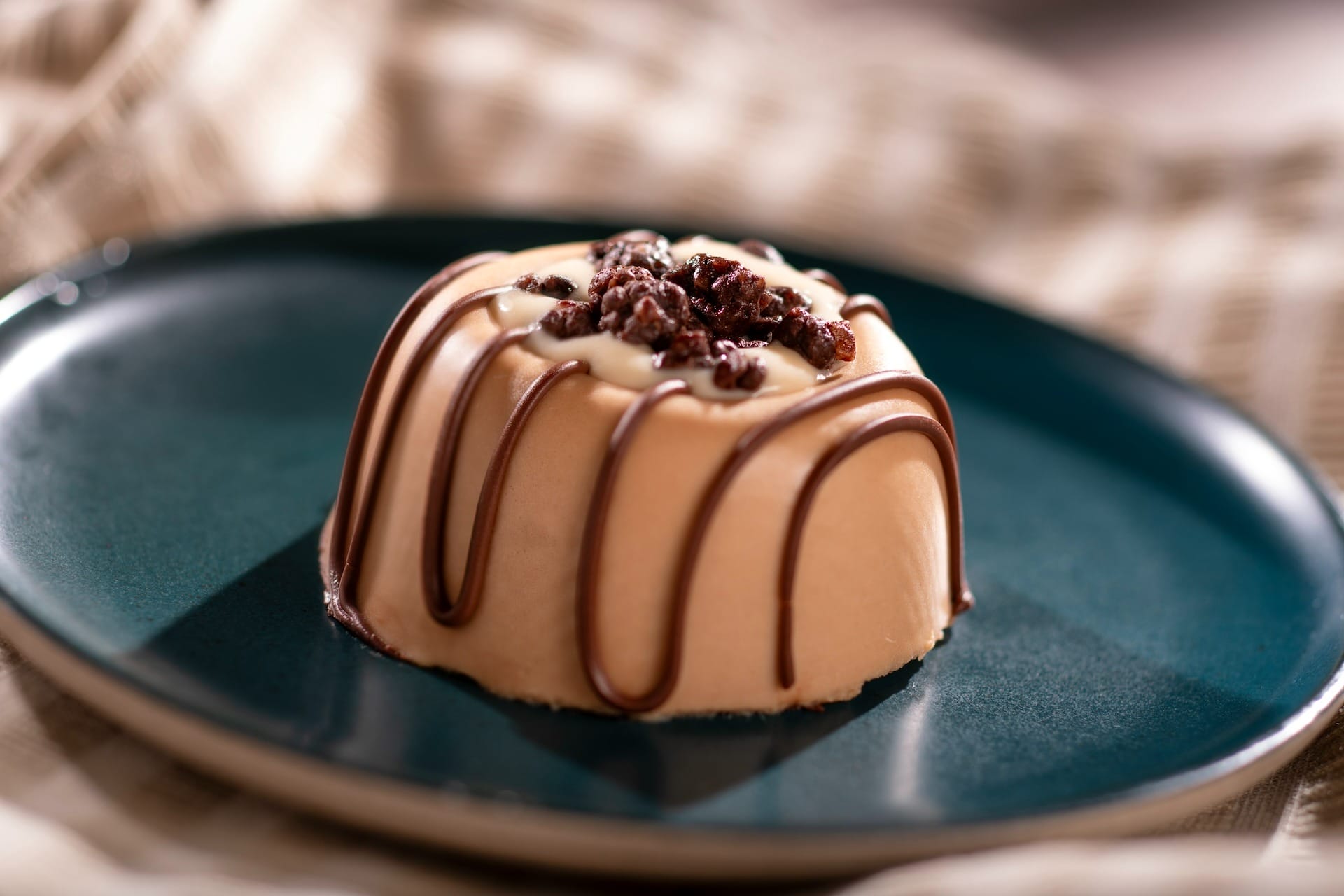A round dessert with chocolate drizzle, served on a dark green plate at the EPCOT Food & Wine Festival.