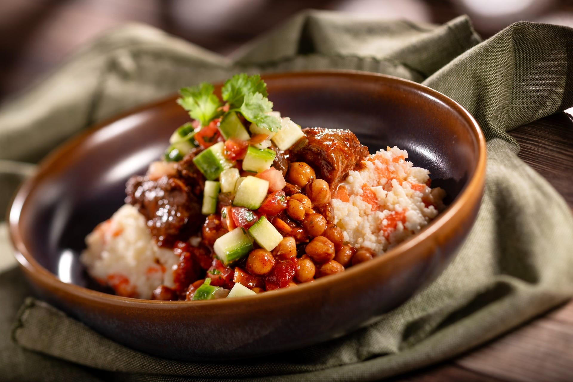 A bowl of rice with chickpeas, beef, cucumber, and salsa—perfect for the 2025 menus at EPCOT Food & Wine Festival.