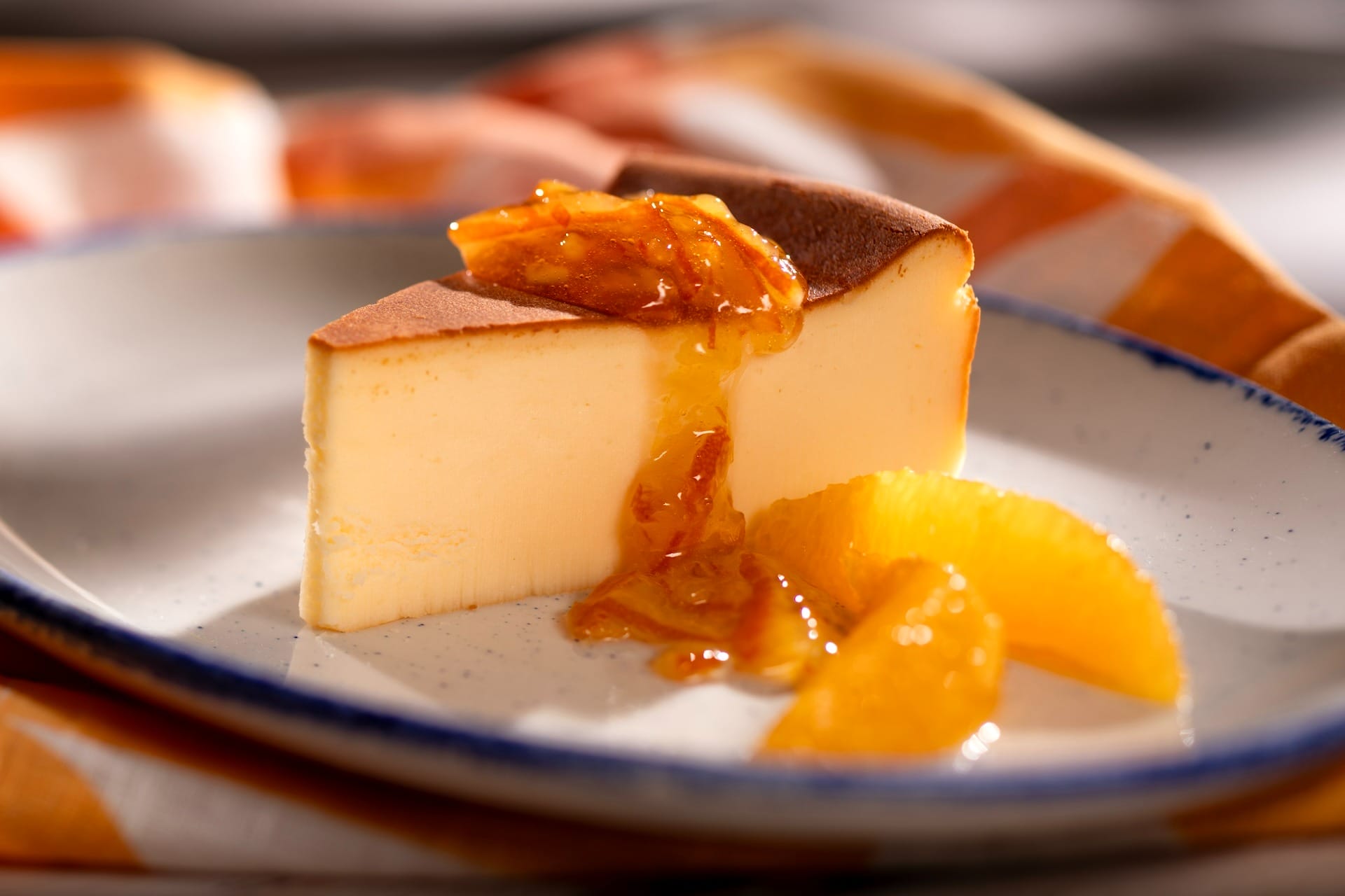 A slice of cheesecake topped with orange marmalade, featured on 2025 menus at the EPCOT Food & Wine Festival.