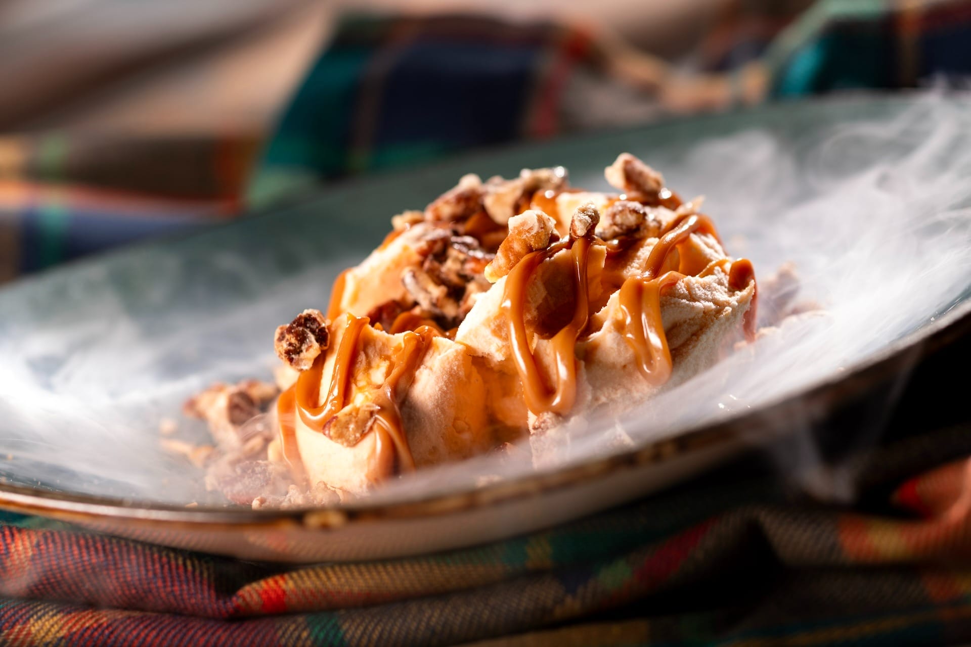 A dessert topped with caramel and nuts sits amid swirling vapor at the EPCOT Food & Wine Festival.