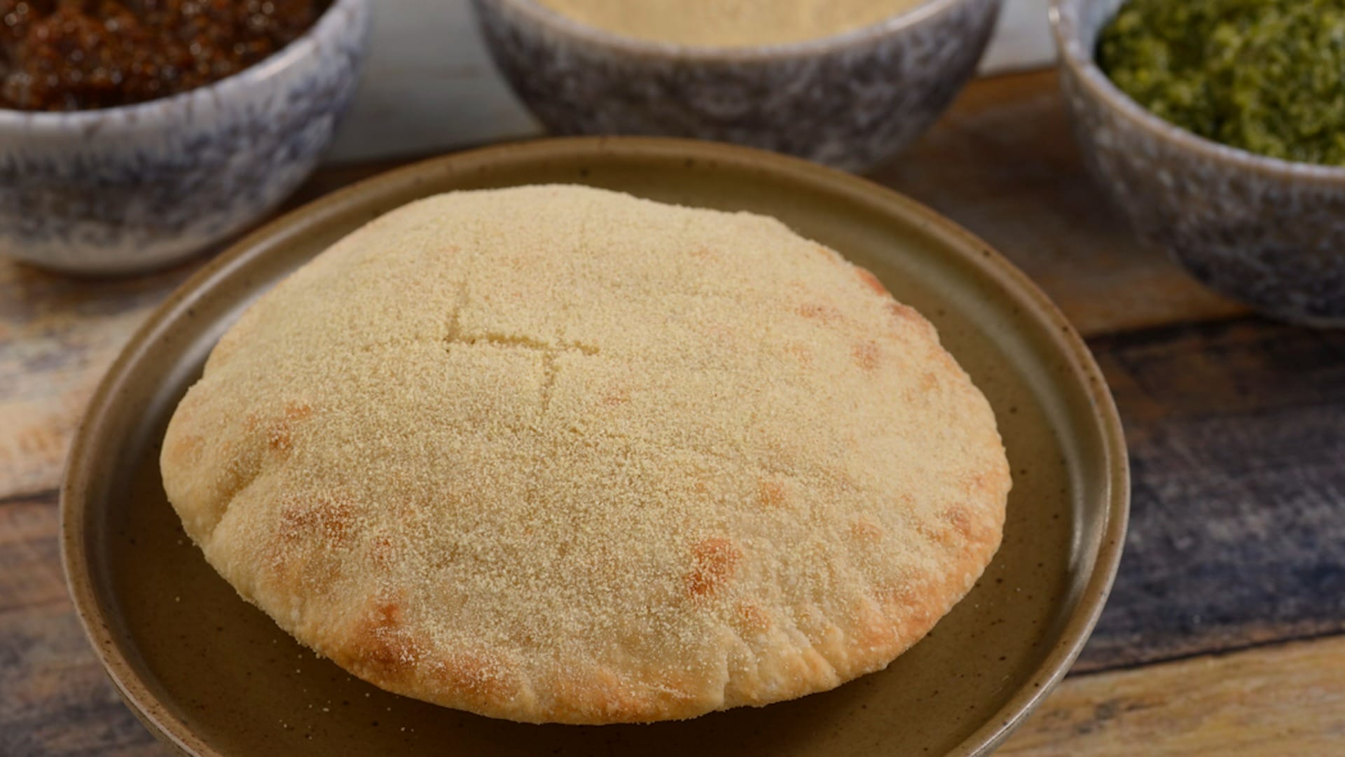 A round, golden, semolina-dusted Moroccan bread, featured on 2025 menus at the EPCOT Food & Wine Festival.