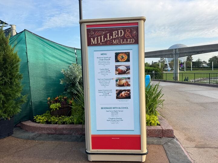 A signboard displays the New Food & Wine "Milled & Mulled" menu and beverages at an outdoor spot with greenery and a dome.