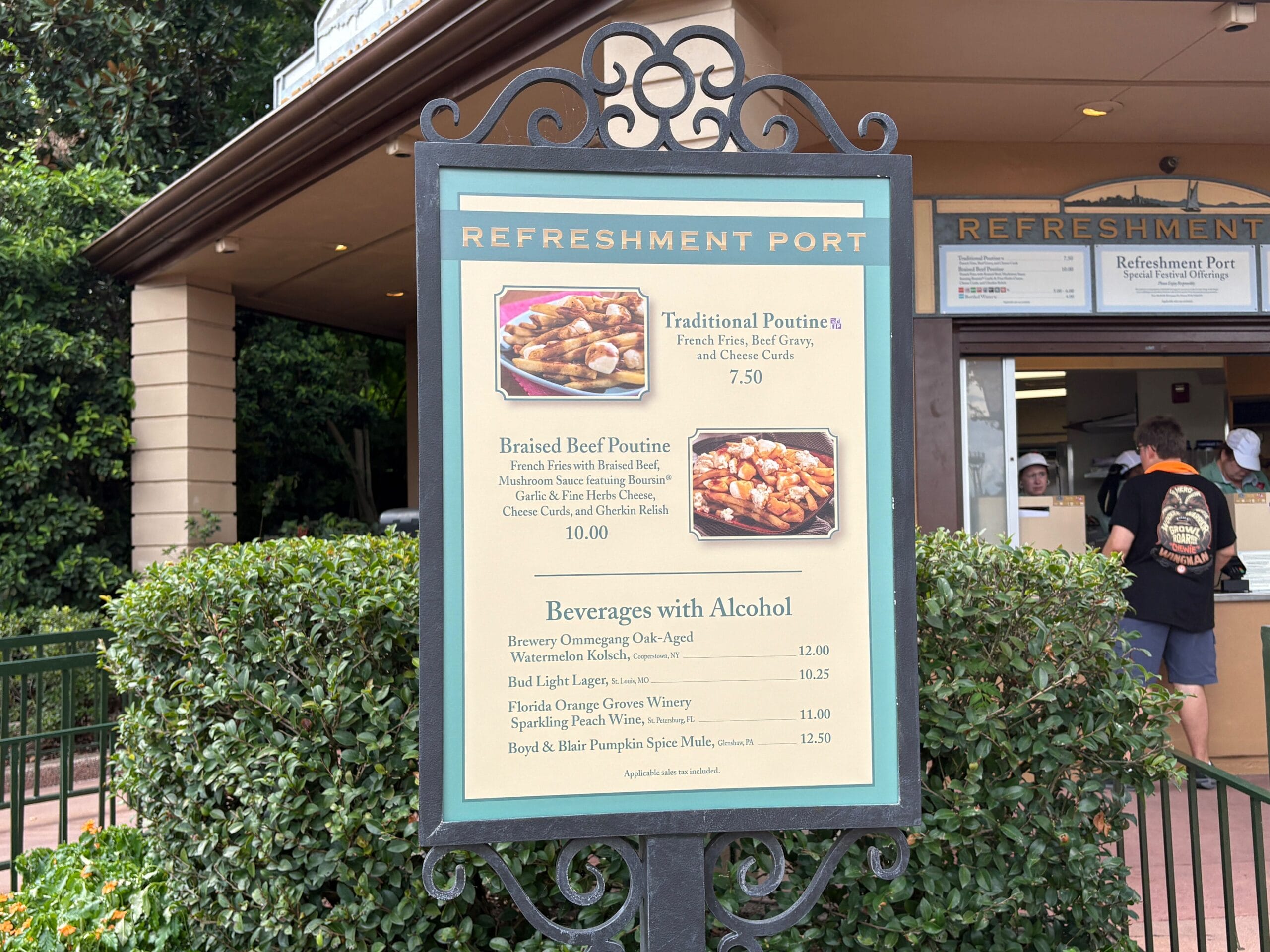 Menu sign at Refreshment Port highlights Food & Wine poutine options and alcoholic drinks, with service window behind.