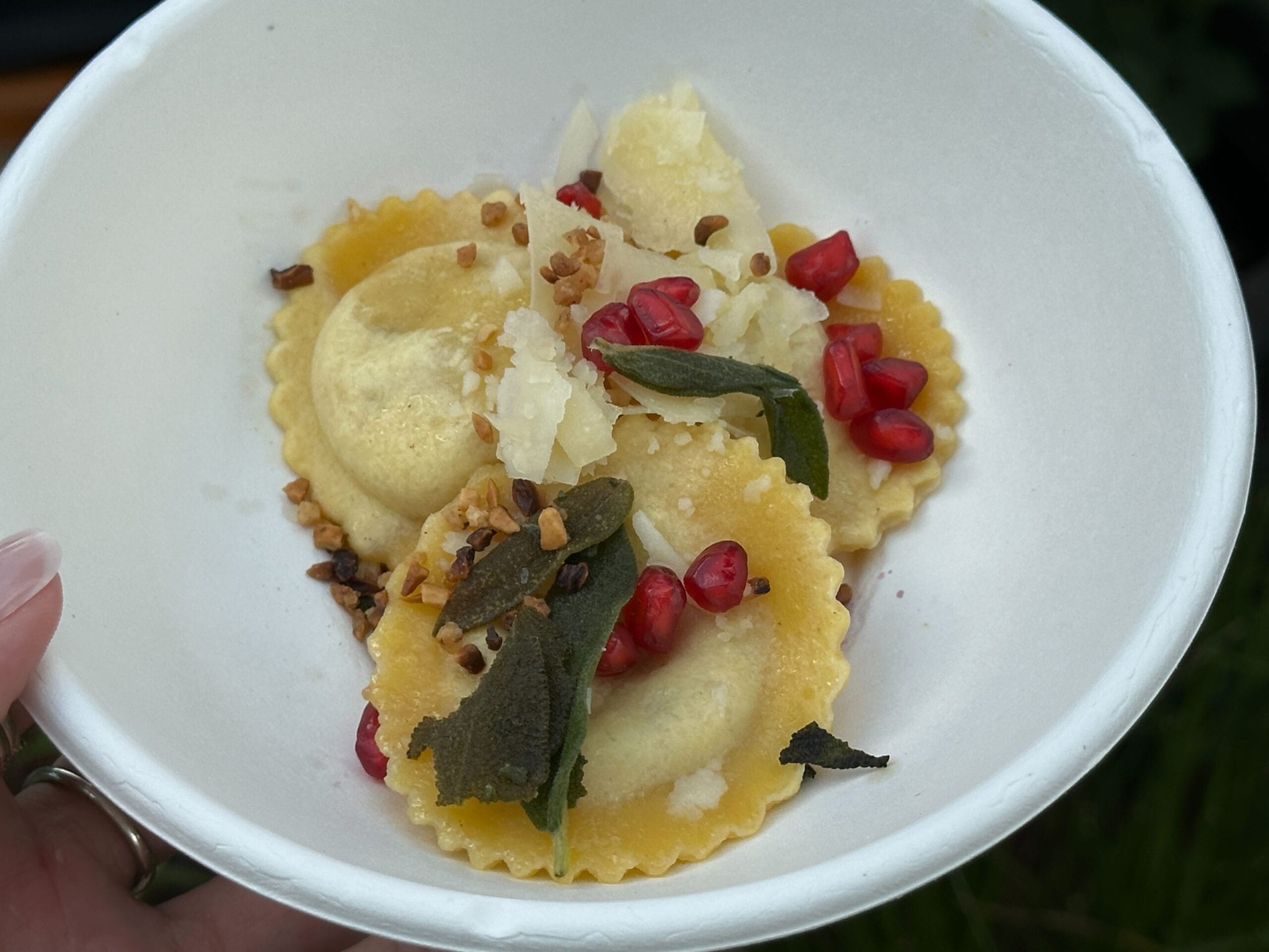 Three ravioli with shaved cheese, pomegranate seeds, crispy sage, and chopped nuts—a Food & Wine delight.