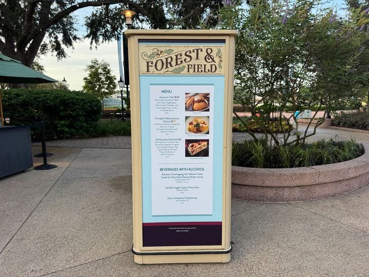 Menu board for "Forest & Field" outdoor eatery, featuring New Food & Wine options, placed on a sidewalk.