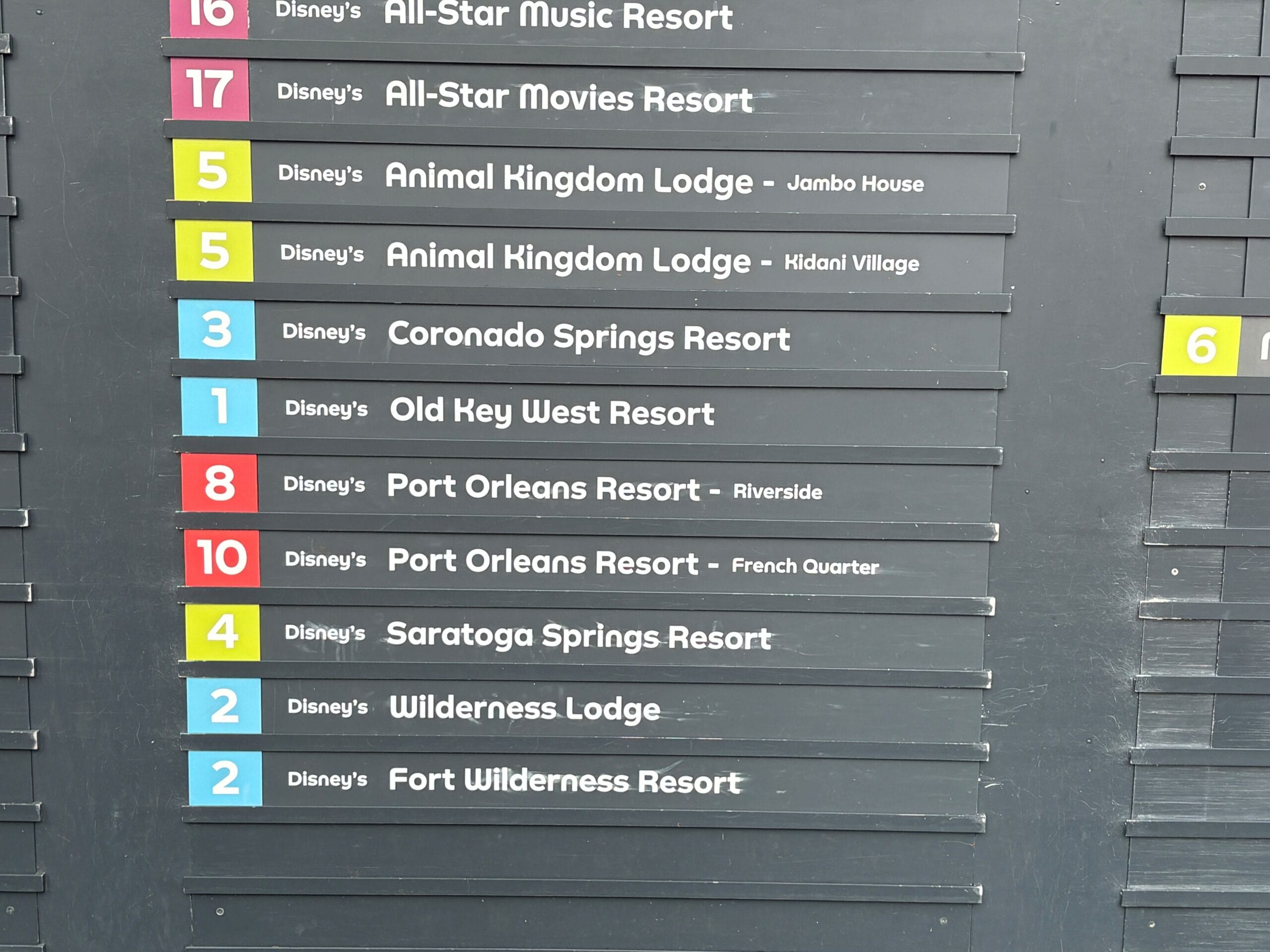 A bus stop sign lists Disney resorts and EPCOT, featuring colored route numbers—reflecting the Bus Stop Expansion.
