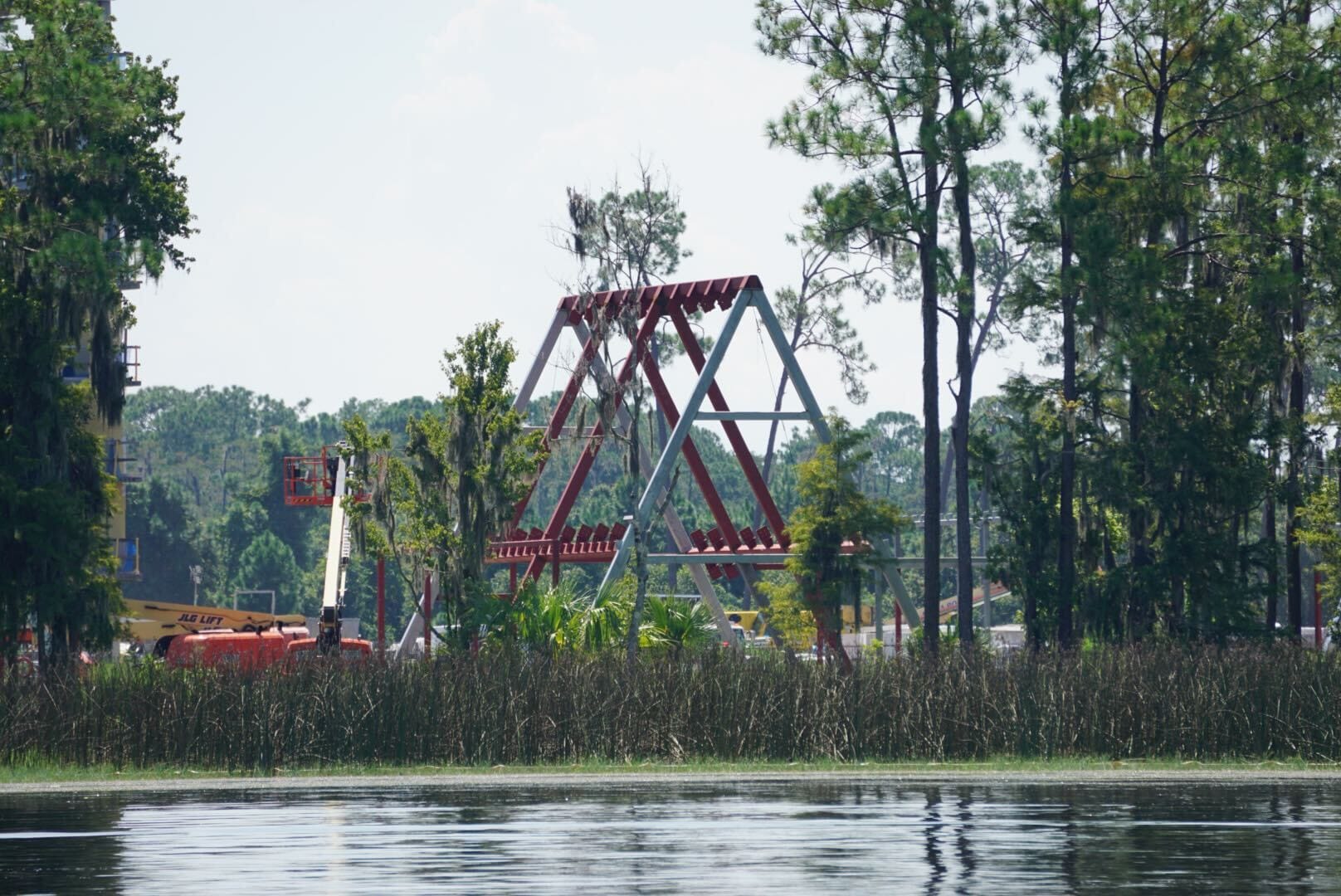 A triangular roller coaster structure under construction near trees and water in the foreground—your Lakeshore Update.