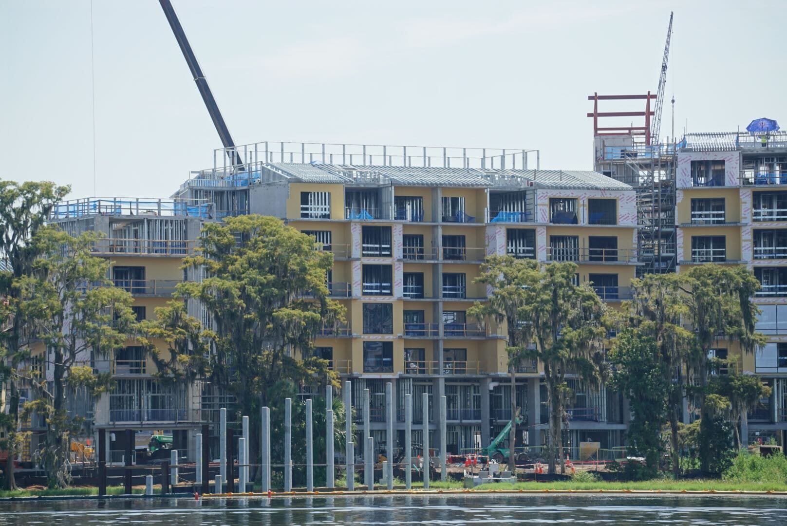 Lakeshore Update: A multi-story lakeside building under construction, with cranes and scaffolding, surrounded by trees.