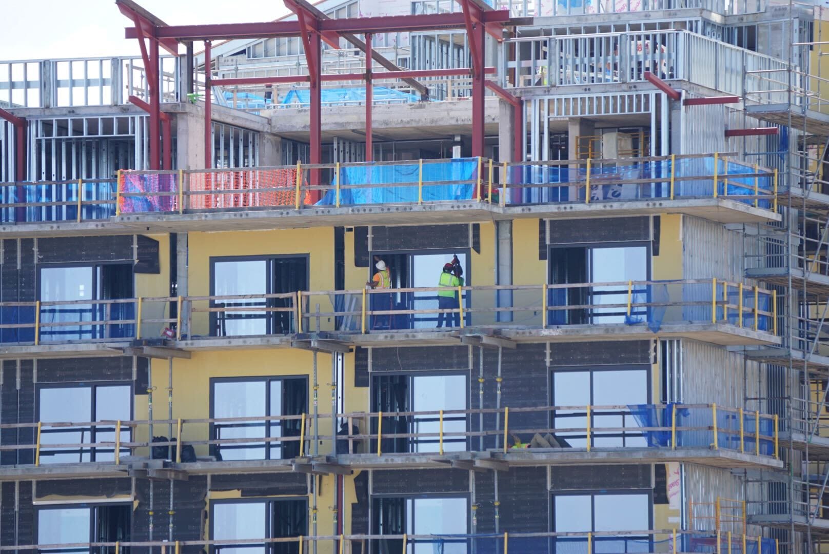 Construction workers stand on the balcony of a partially finished building in this Lakeshore Update.