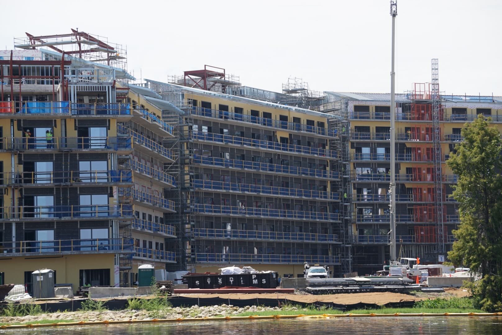 Lakeshore Update: A multi-story building under construction with scaffolding and materials near a body of water.