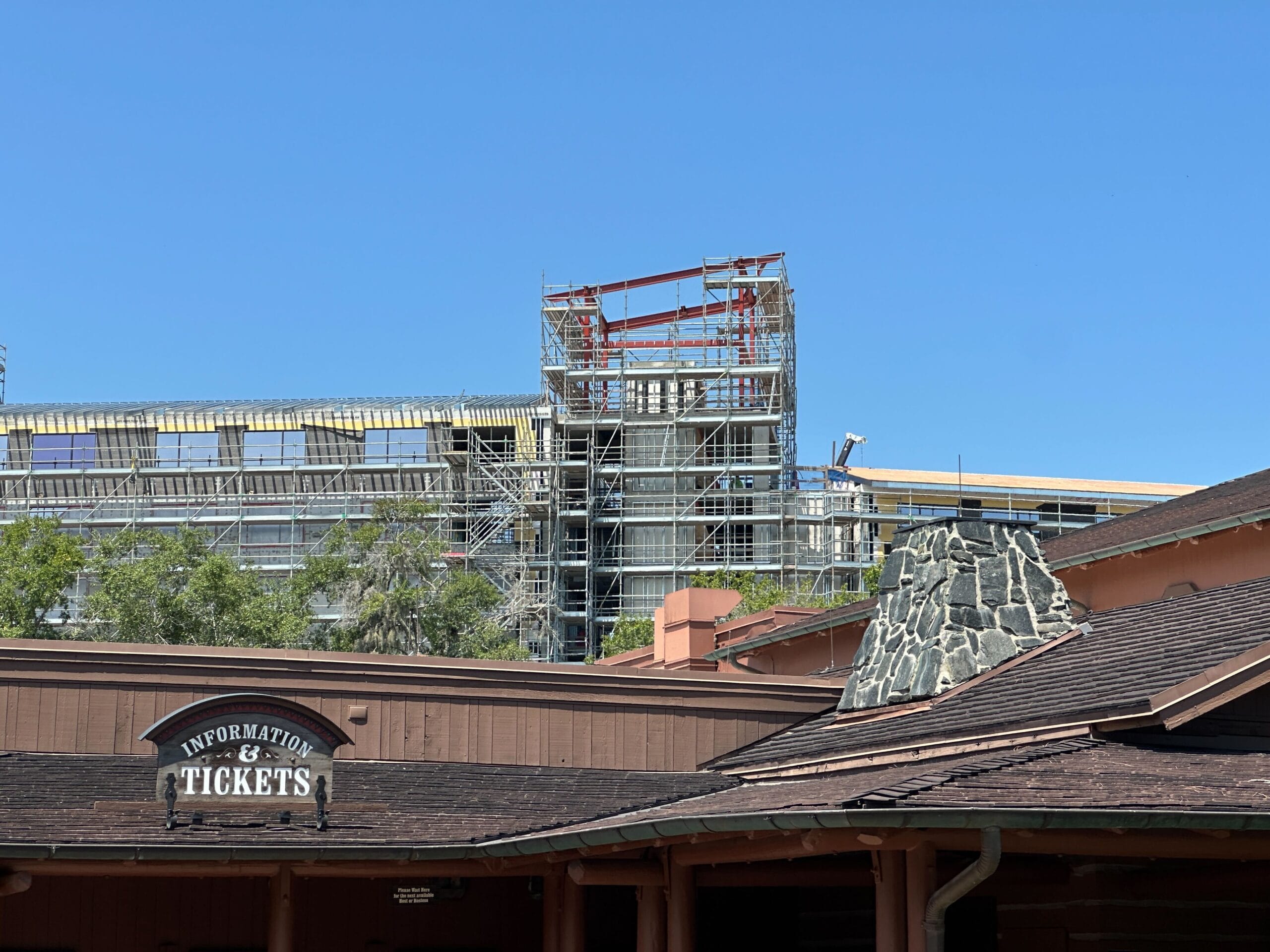 Scaffolding covers a large building under construction in the Lakeshore area behind a rustic information and tickets booth.