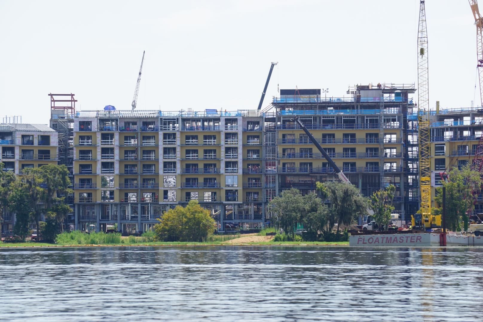Lakeshore Update: A multi-story building rises near the water, cranes and trees framing the construction scene.
