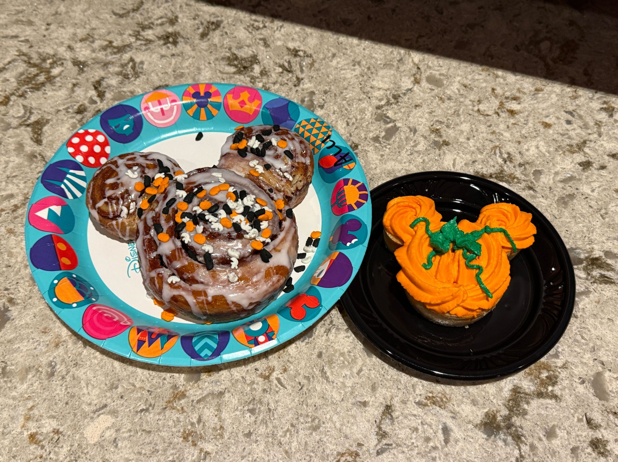 A Mickey-shaped cinnamon roll with Halloween sprinkles, perfect for food reviews at Mickey's Not So Scary Halloween Party.