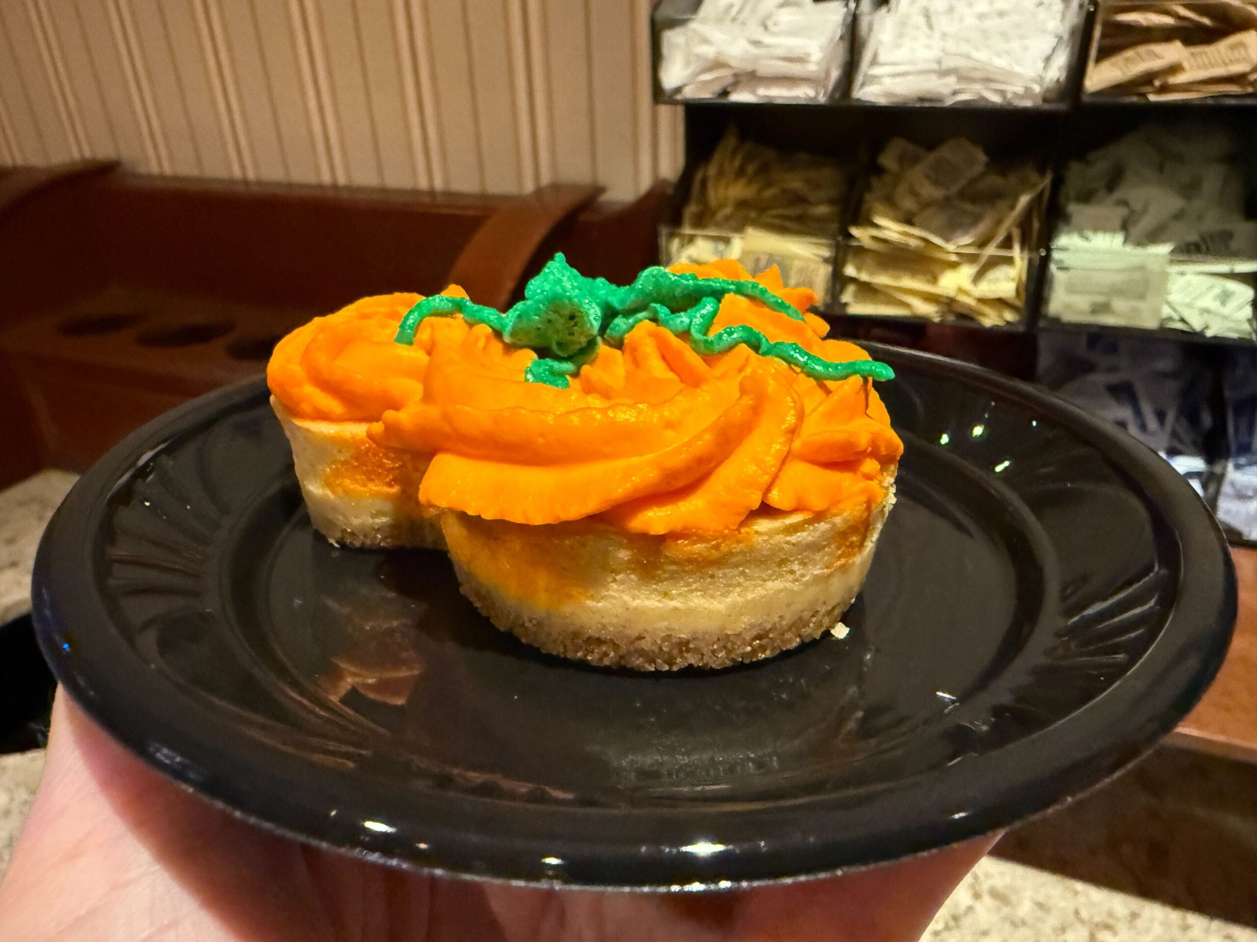A dessert shaped like Mickey Mouse with orange frosting, perfect for food reviews at Mickey's Not So Scary Halloween Party.