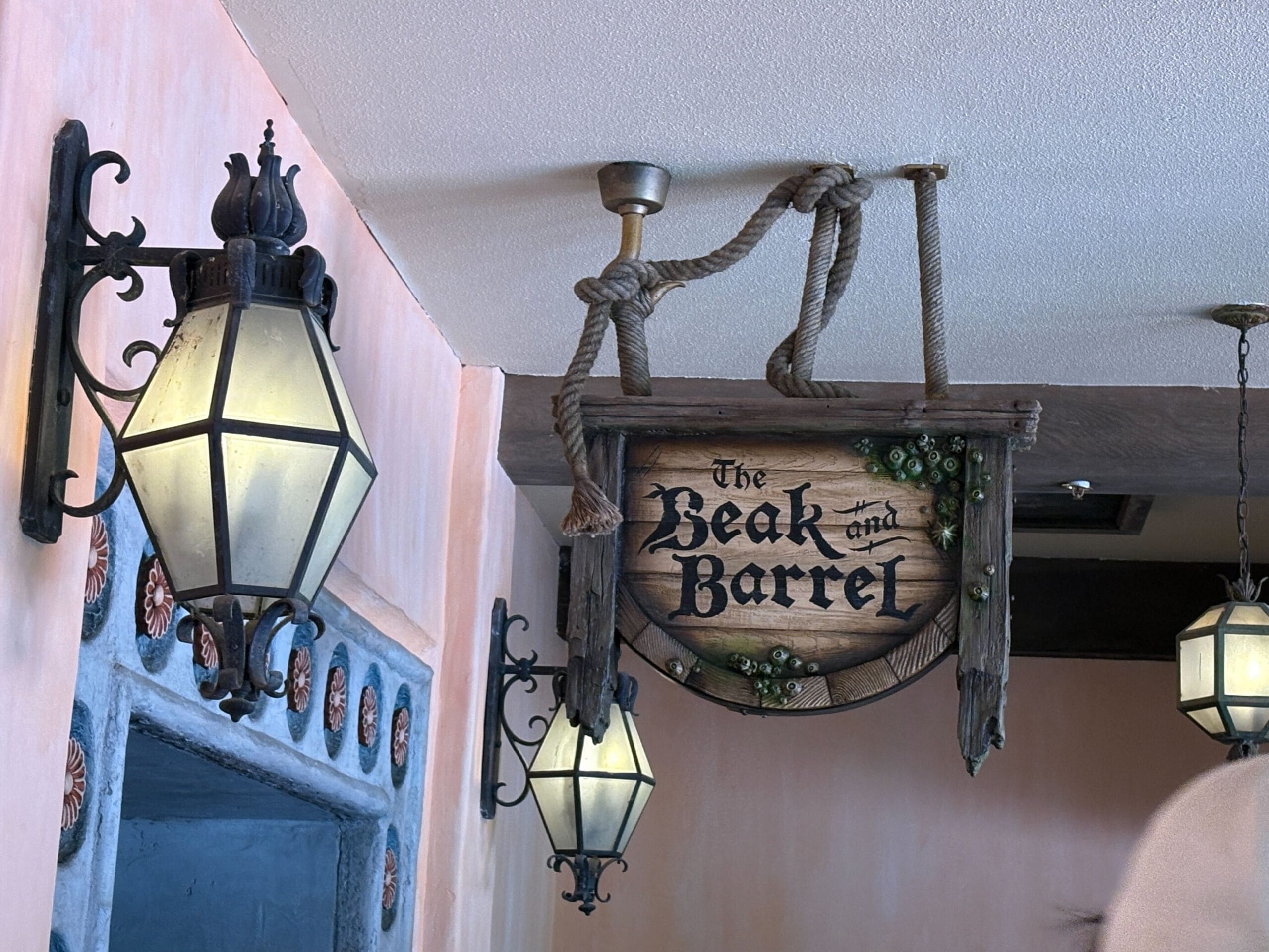 Hanging wooden sign reading “The Beak and Barrel” with lanterns—perfect spot for your next Beak and Barrel review.