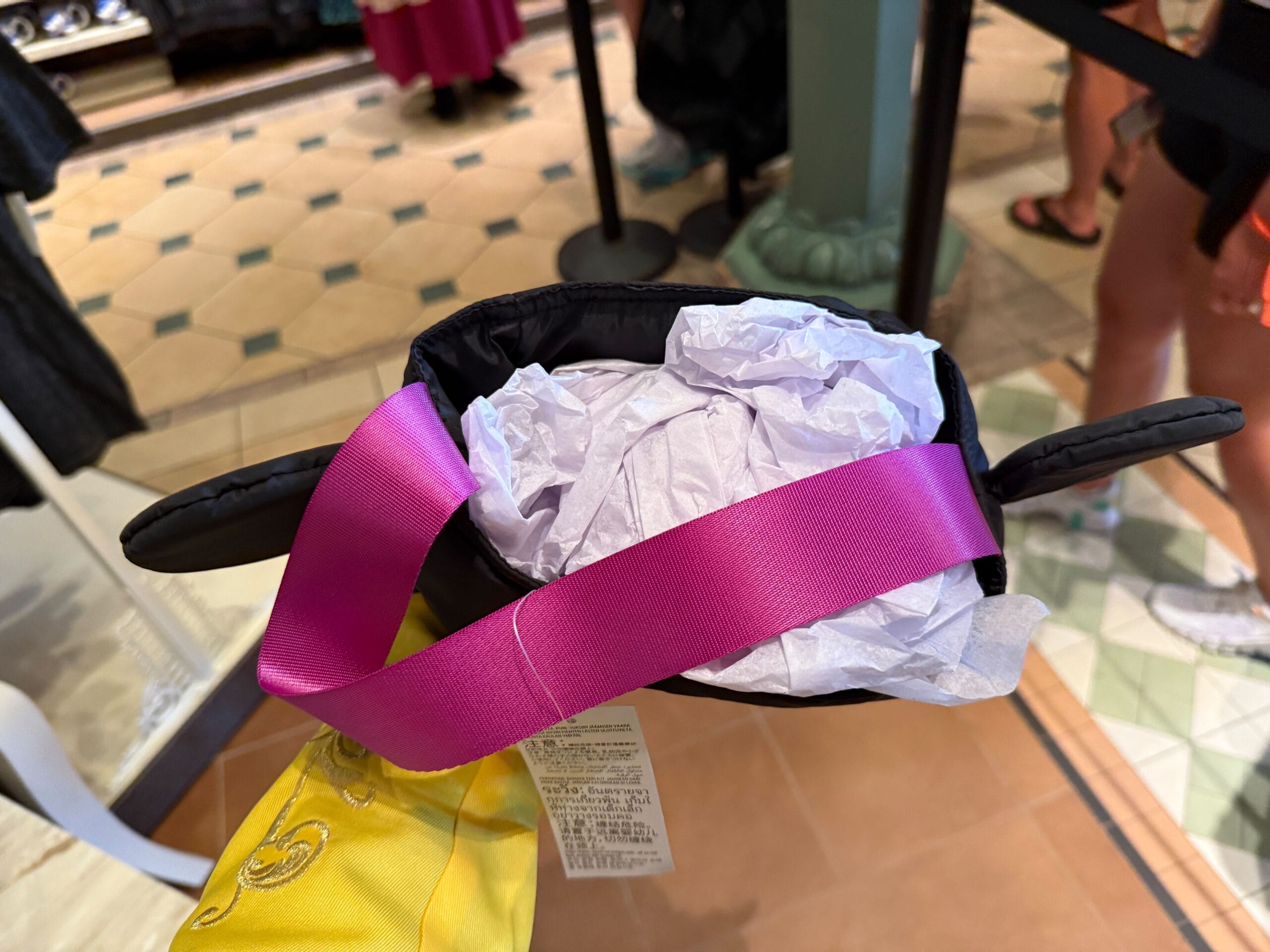 A person holds a small bag with black cat ears—part of the 2025 merchandise for Mickey's Not So Scary Halloween Party.