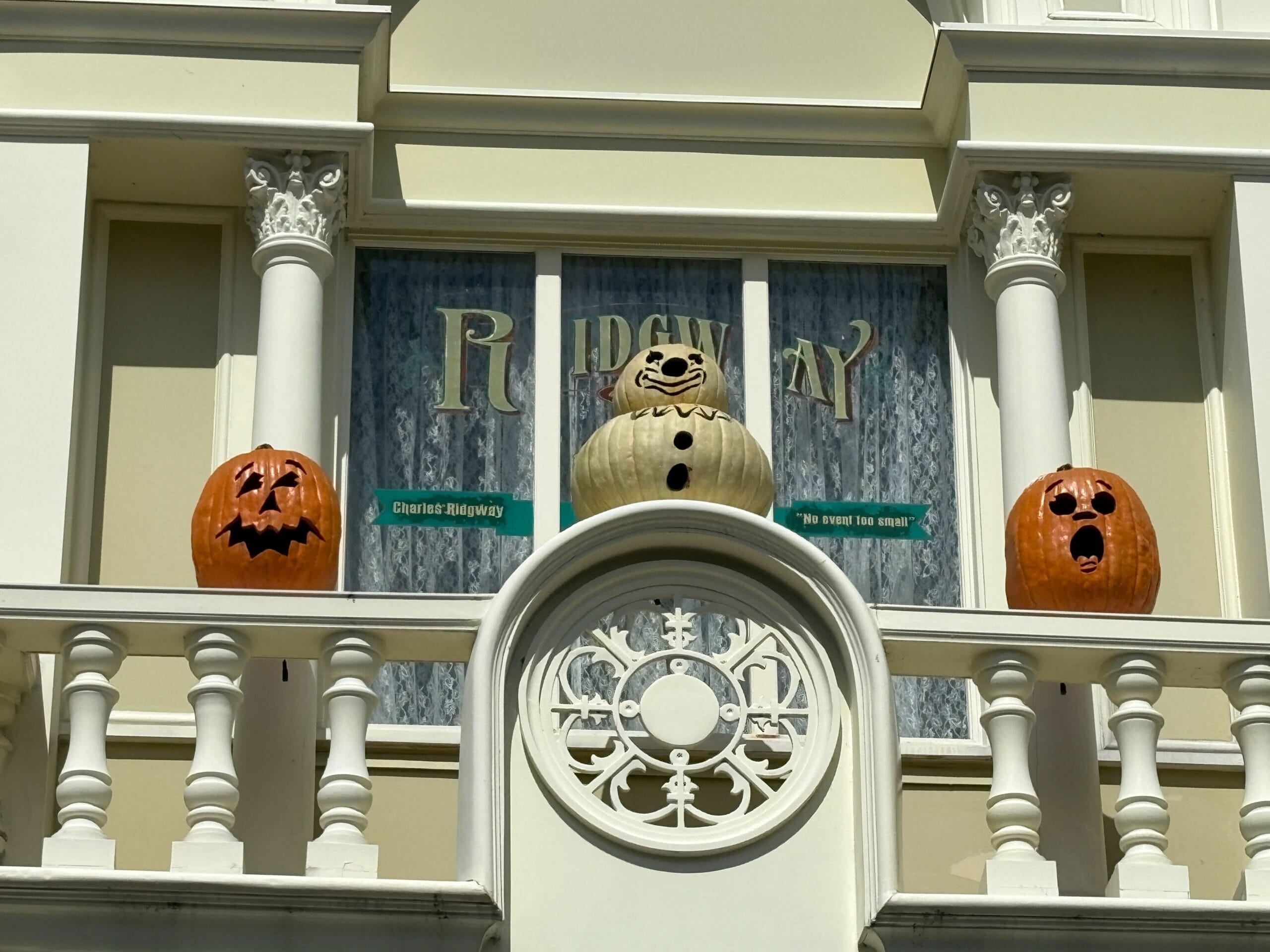 Three carved pumpkins with faces sit on a balcony railing, adding Halloween decor perfect for Magic Kingdom vibes.