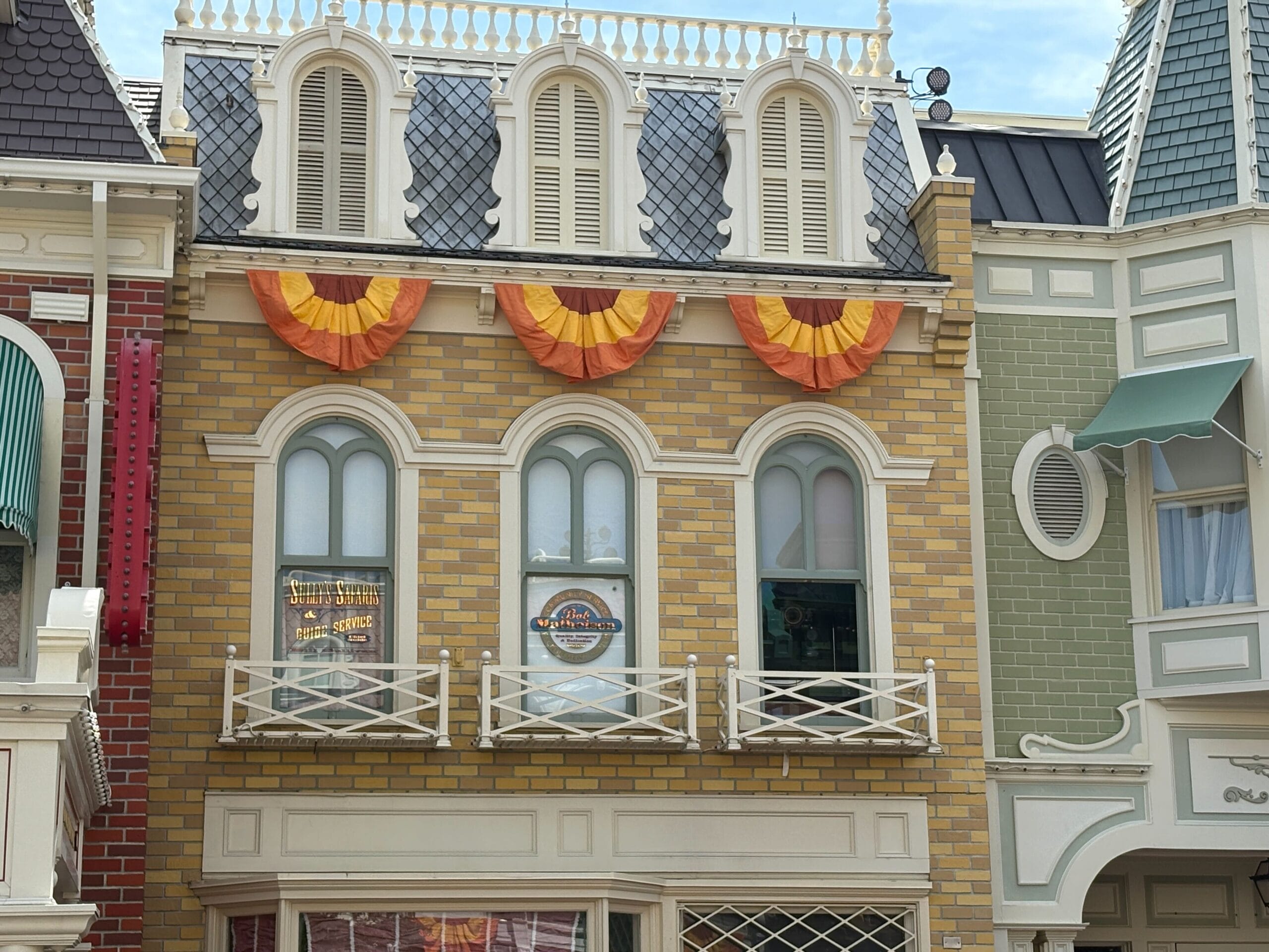 A yellow brick building with arched windows, Halloween decor, orange banners, and decorative white trim.