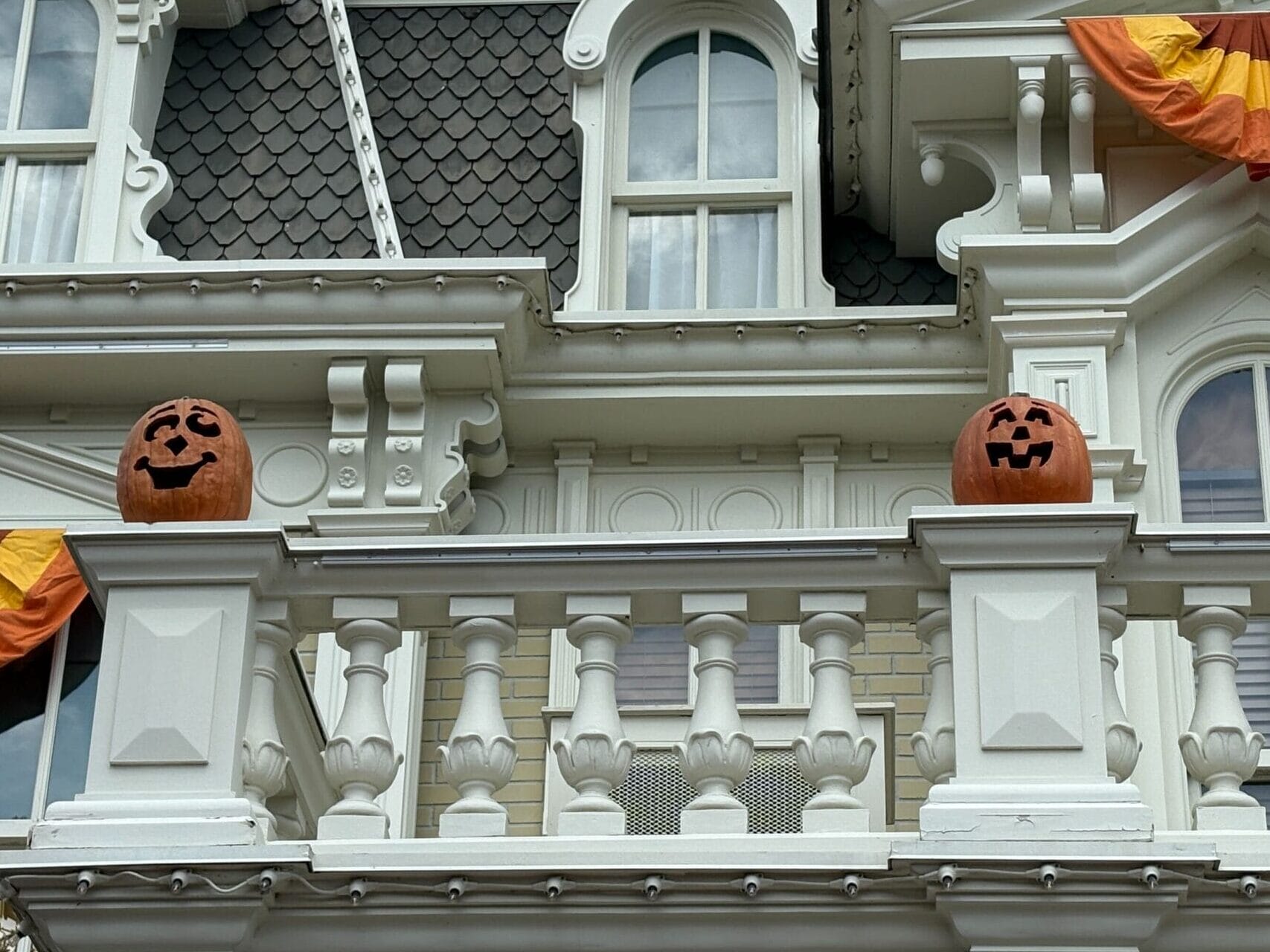 White building with First Wave Halloween decor and two jack-o'-lanterns on the Magic Kingdom balcony railing.