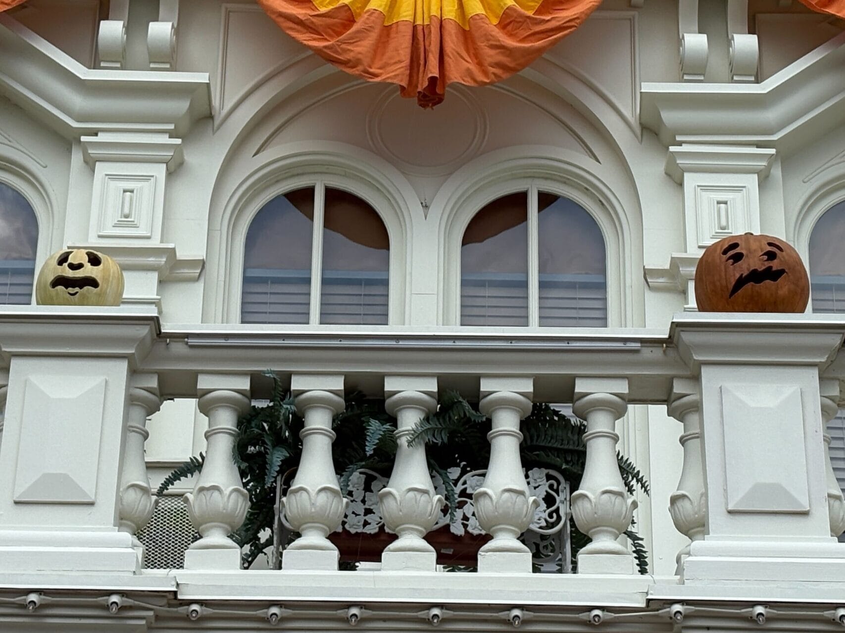 White City Hall at Magic Kingdom with Halloween decor—orange bunting and jack-o'-lanterns on the balcony.