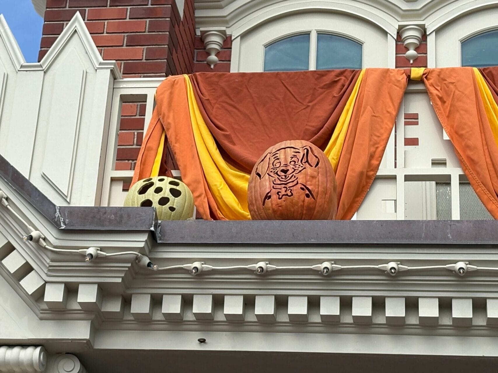 Halloween-themed pumpkins, including a Scooby-Doo carving, add festive Magic Kingdom Halloween Decor to the draped balcony.