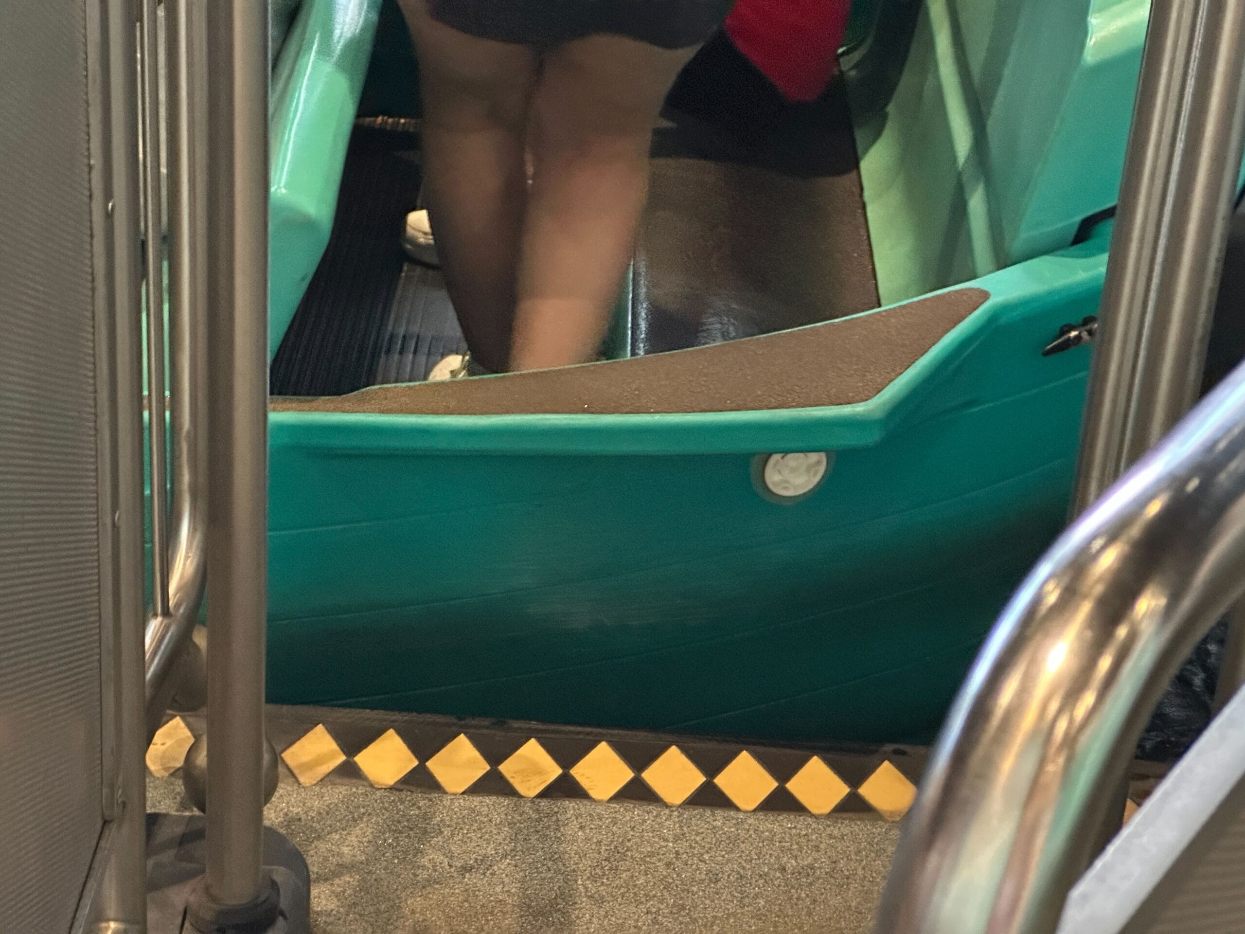 Person stepping into a teal ride vehicle with yellow safety markings at Magic Kingdom’s it’s a small world new boats.