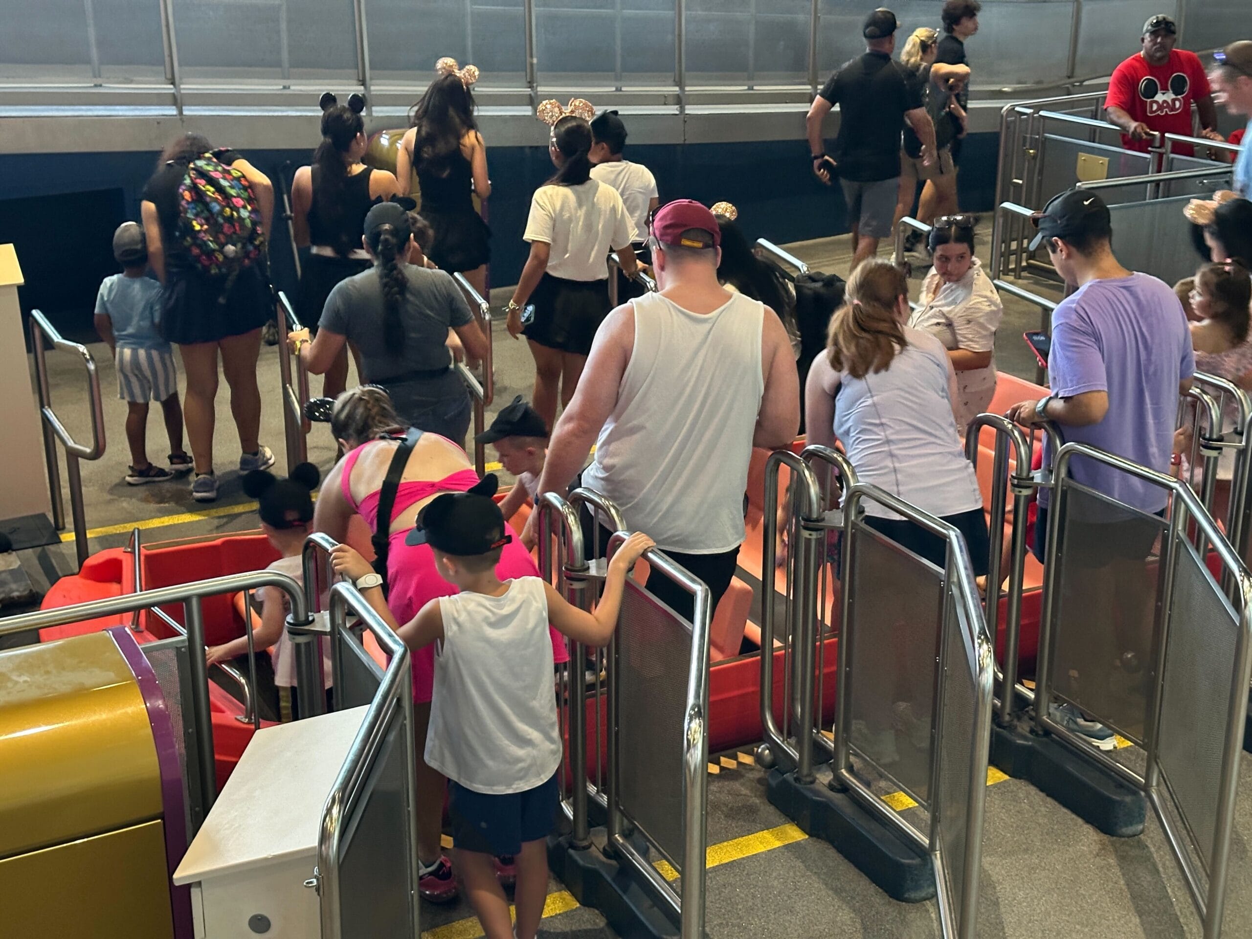 Guests at Magic Kingdom board new boats for it’s a small world, with families walking down busy indoor ramps and stairs.